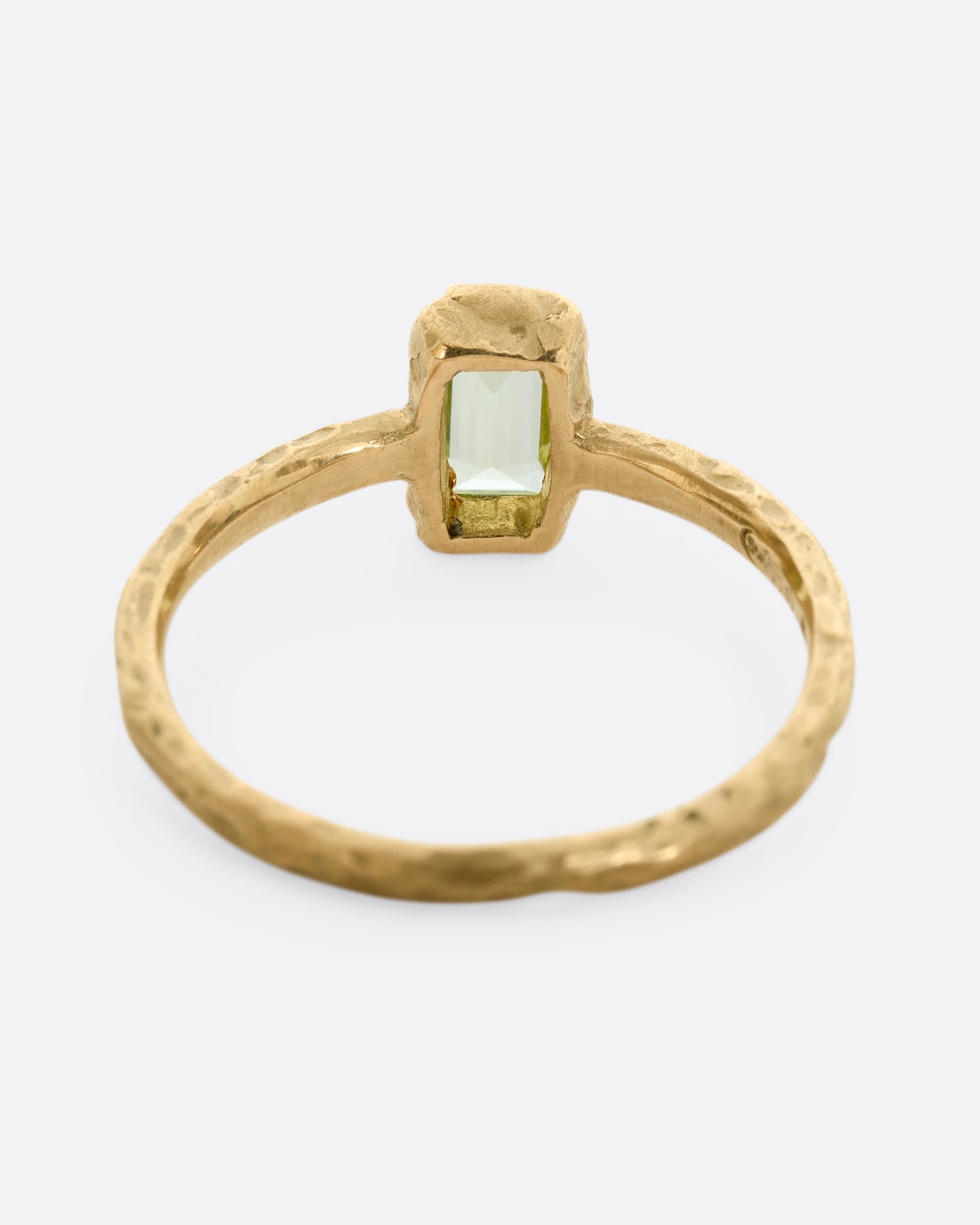A textured yellow gold ring with a rectangular peridot. Shown from the back.