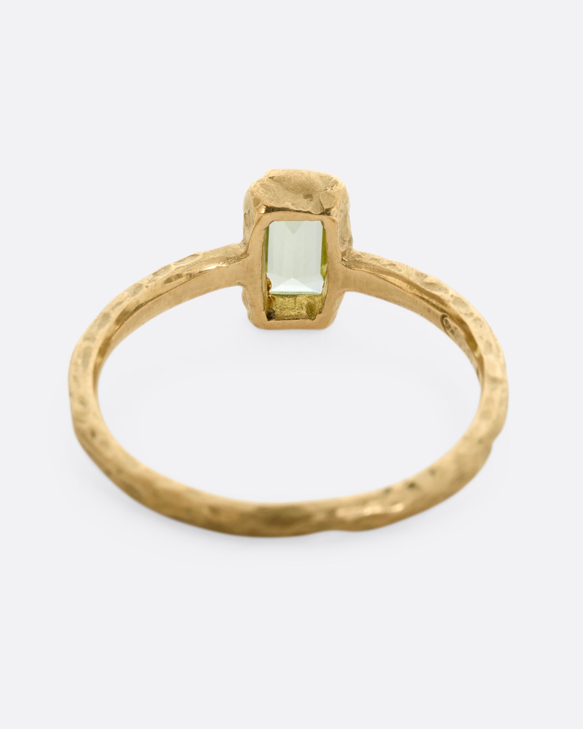 A textured yellow gold ring with a rectangular peridot. Shown from the back.