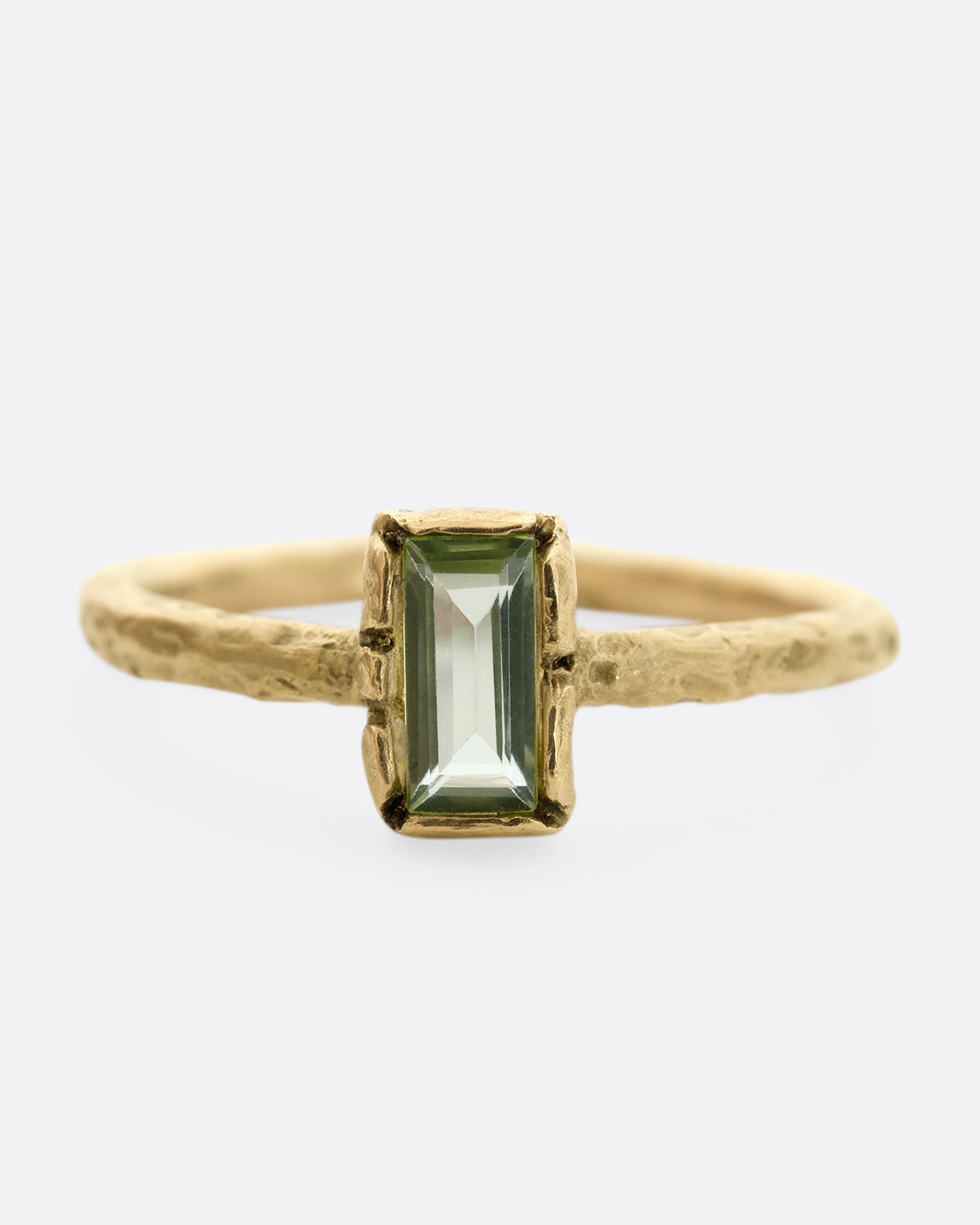 A textured yellow gold ring with a rectangular peridot. Shown from the front.