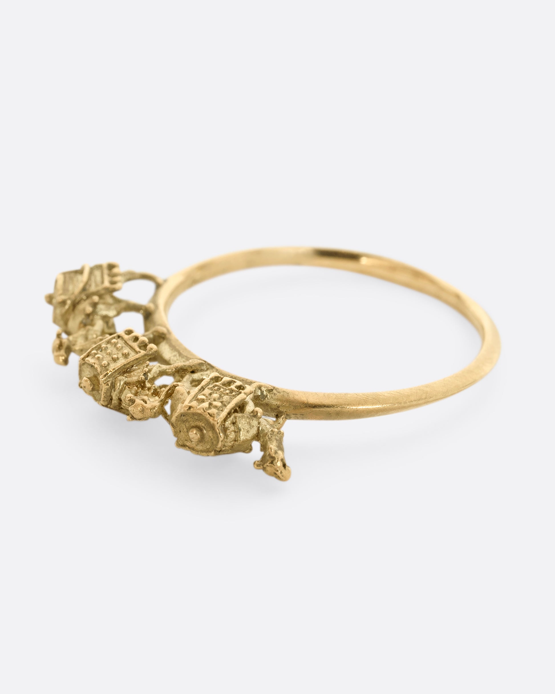 A yellow gold ring with a caravan of three camels walking across the top of the band. Shown laying flat.