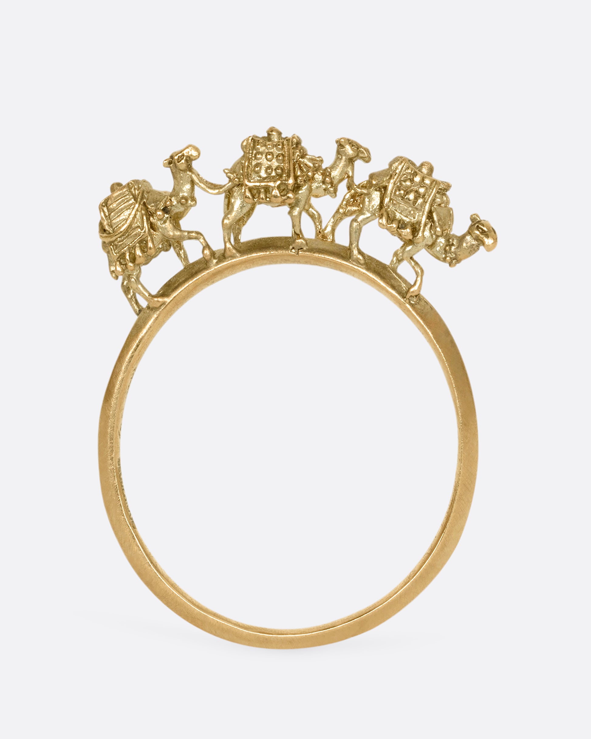 A yellow gold ring with a caravan of three camels walking across the top of the band. Shown from the back standing up.