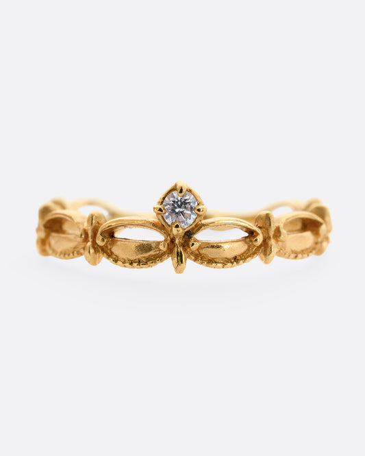 A yellow gold tiara shaped band with curved and textured details and a round white diamond at the center. Shown from the front.