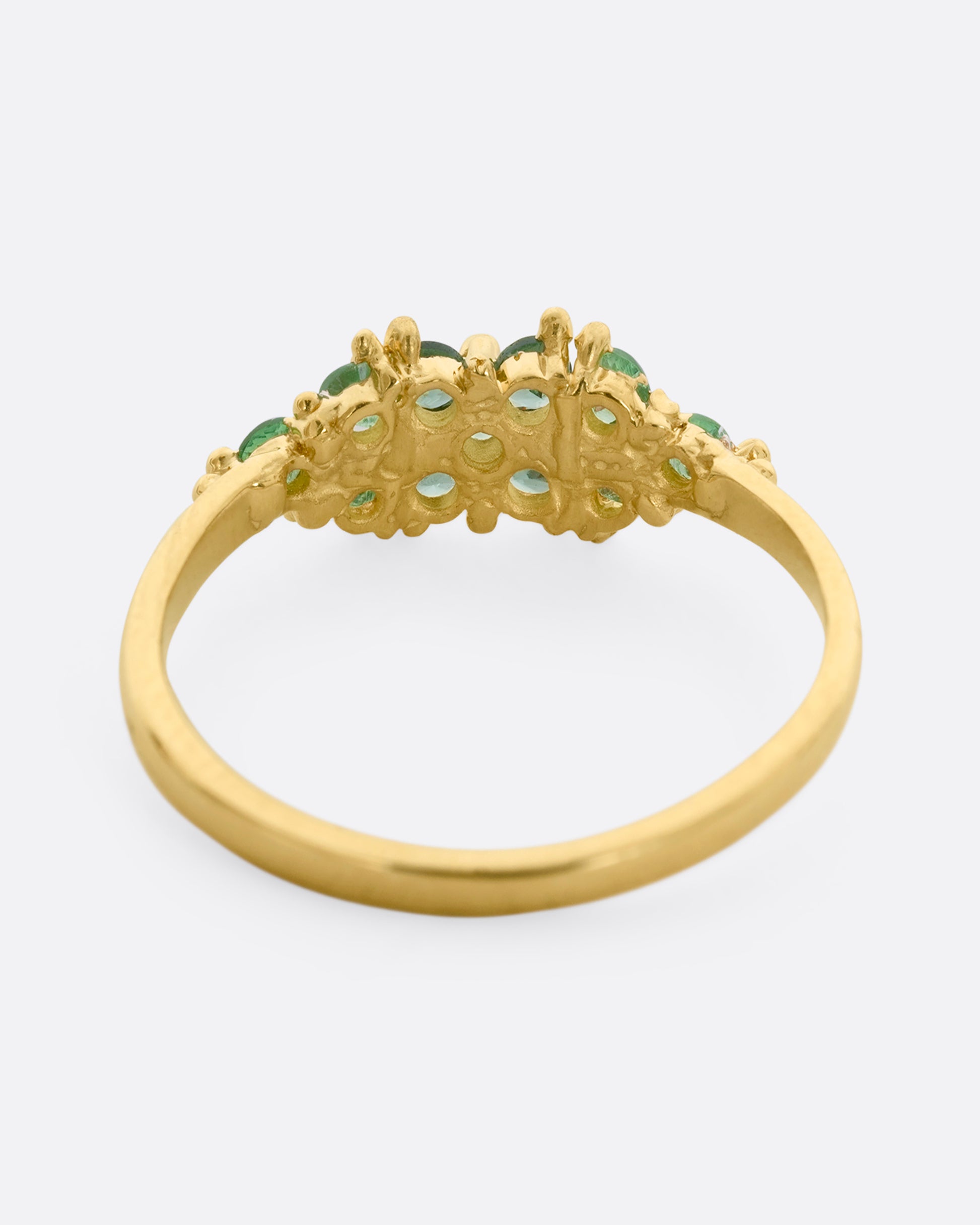 A yellow gold ring with a cluster of eleven green sapphires and tsavorite. Shown from the back.