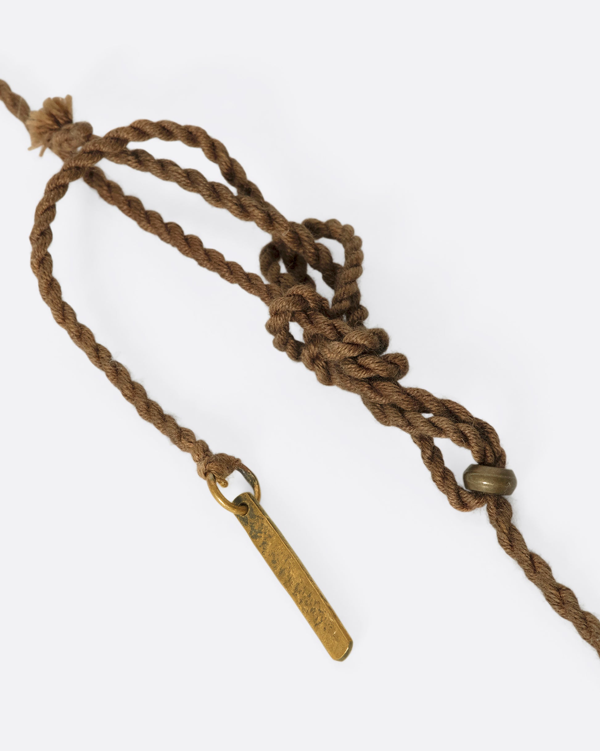 A stunning pre-Columbian carnelian bullet pendant suspended in 22k gold from a lengthy, twisted brown chord
