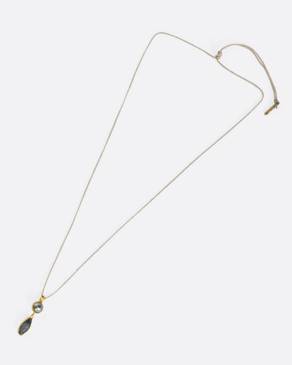 Yellow gold Tahitian pearl and sapphire pendant necklace laid flat, showing the full length of the cord