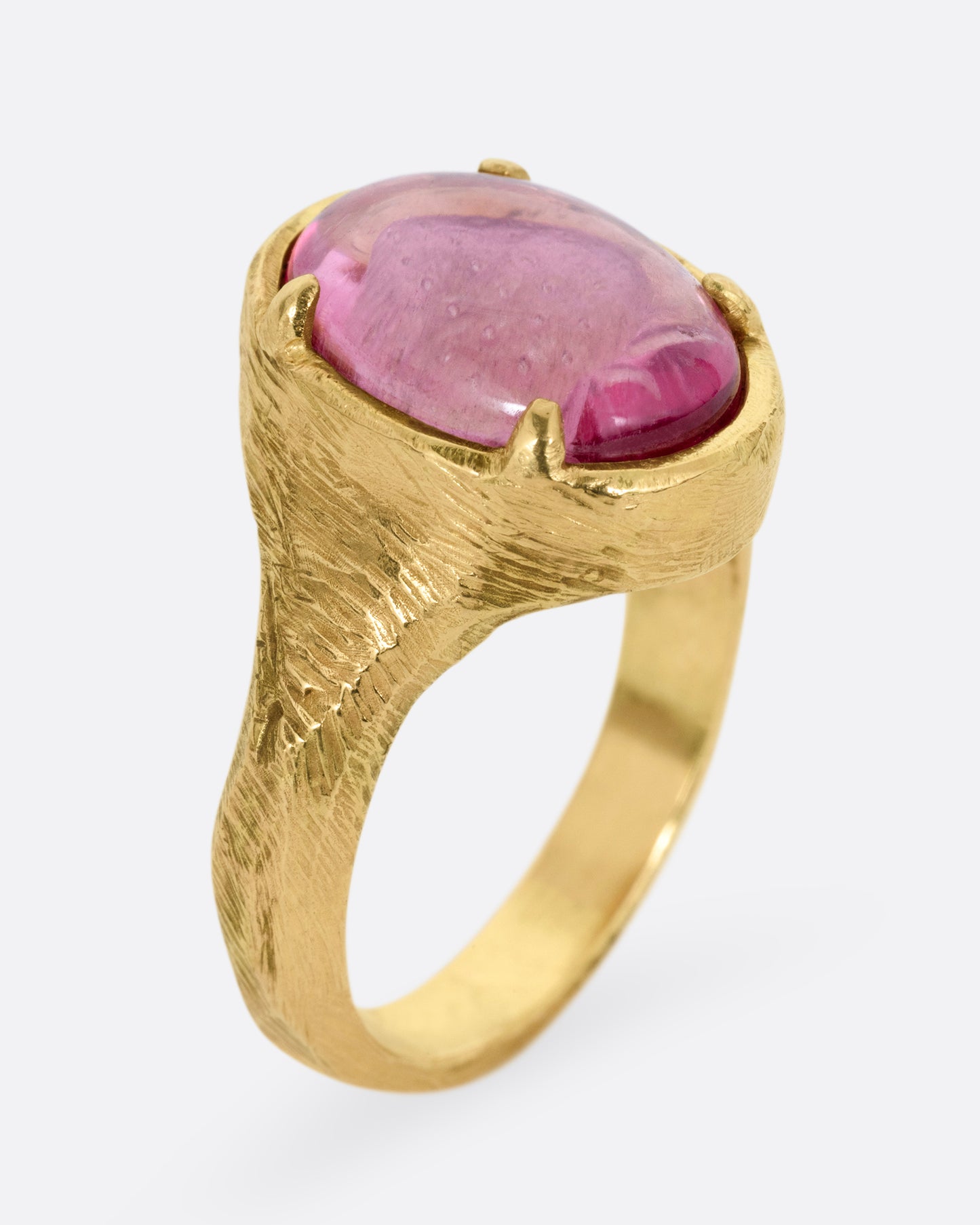 A yellow gold signet ring with a carved strawberry in a prong set pink garnet. Shown from the side standing up.
