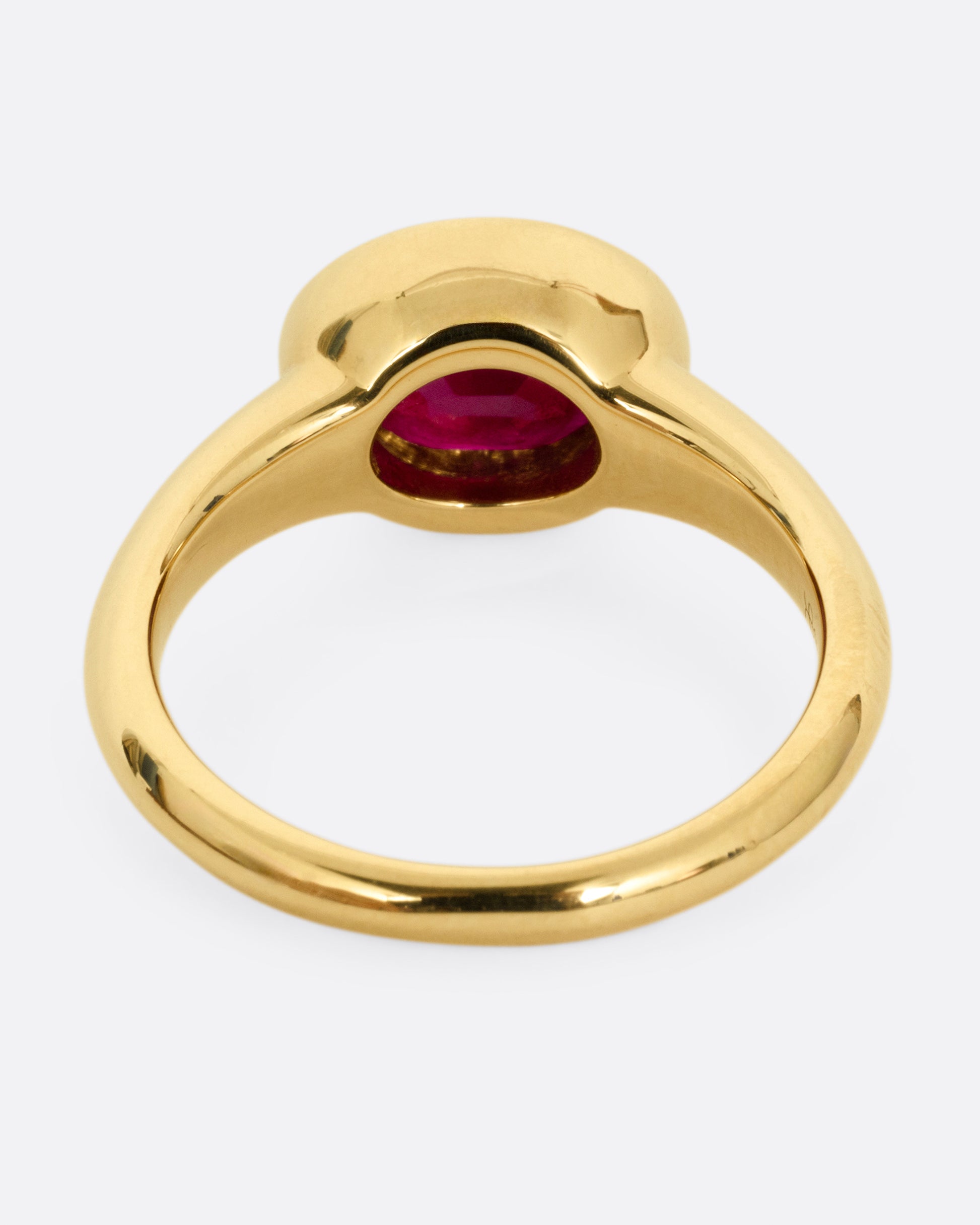 A yellow gold ring with a navy enamel and ruby center. Shown from the back.