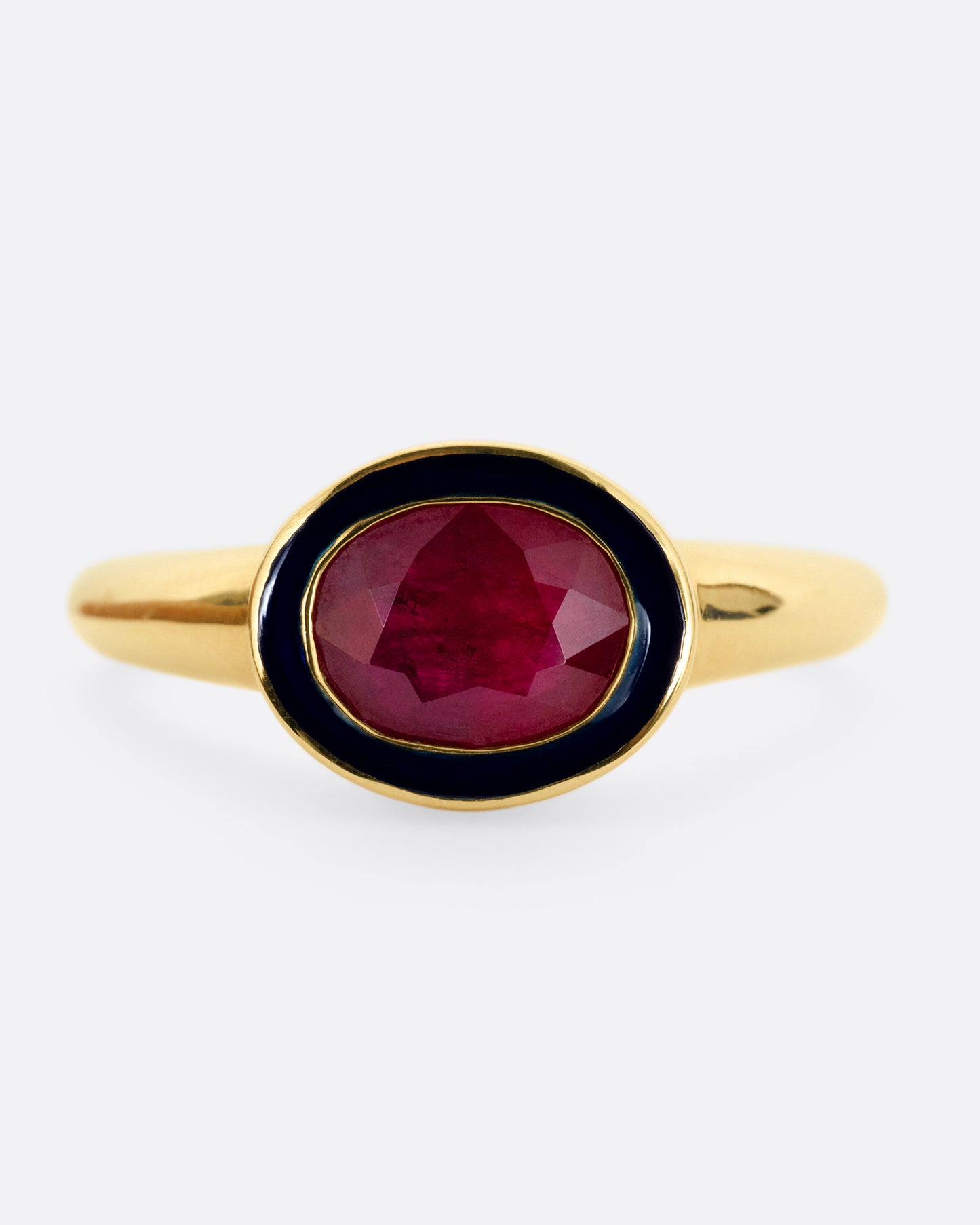 A yellow gold ring with a navy enamel and ruby center. Shown from the front.