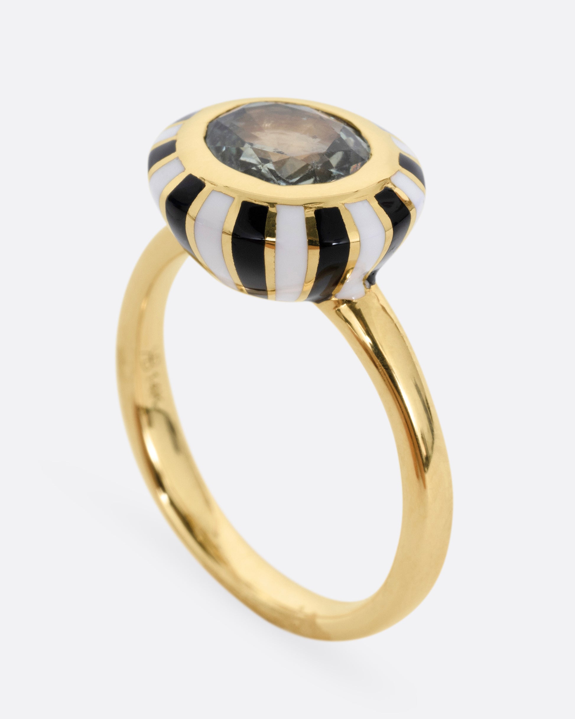 A yellow gold ring with an enamel checkerboard pattern around a green sapphire, shown standing up from the side.
