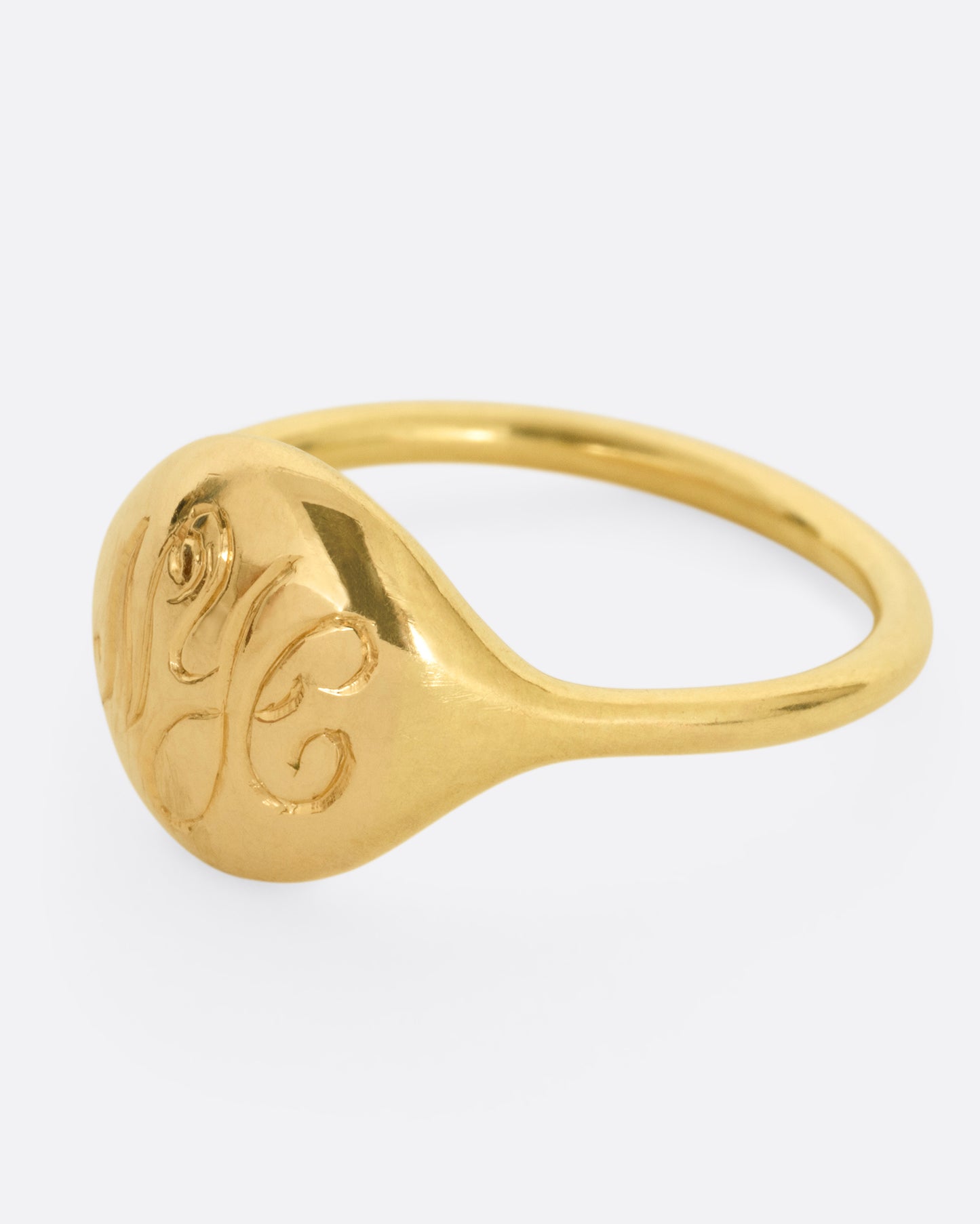 A yellow gold ring with NYC in cursive script. Shown from the side.