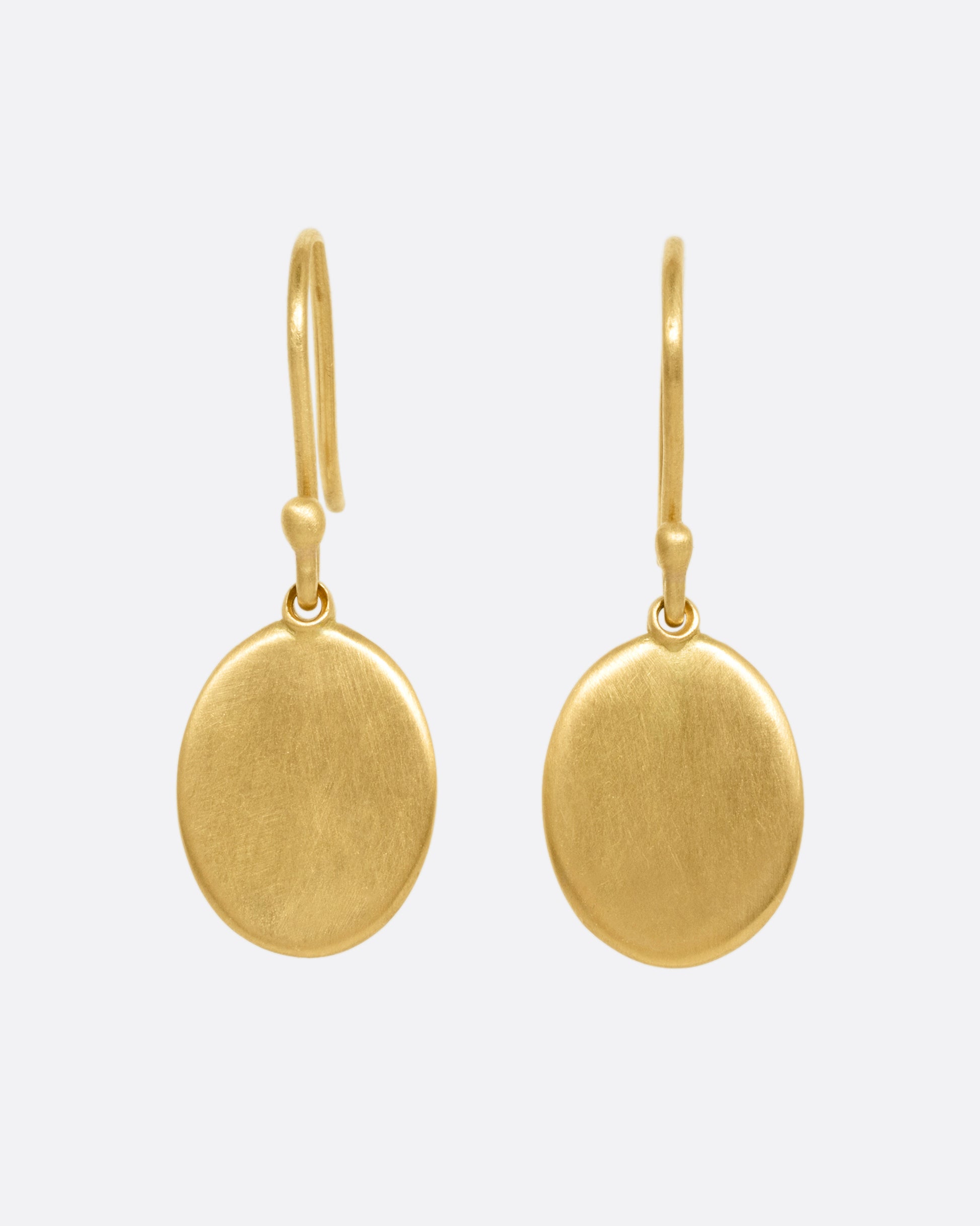 A pair of yellow gold hook earrings with oval dangles, shown from the front.