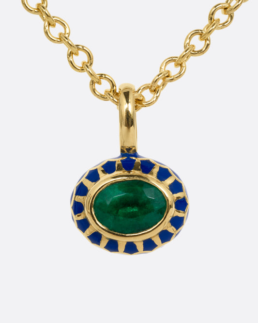 A yellow gold cable chain necklace with a pendant with a blue enamel pattern around an emerald. The pendant has a domed silhouette and floral enamel motif on its reverse. Shown from the front.