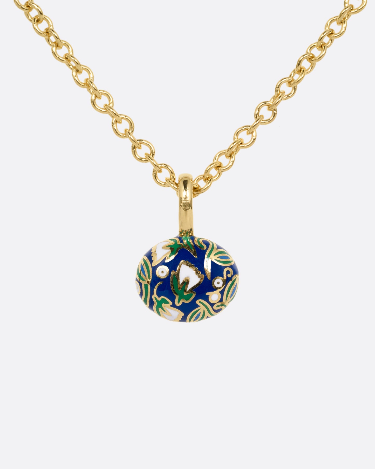 A yellow gold cable chain necklace with a pendant with a blue enamel pattern around an emerald. The pendant has a domed silhouette and floral enamel motif on its reverse. Shown from the back.