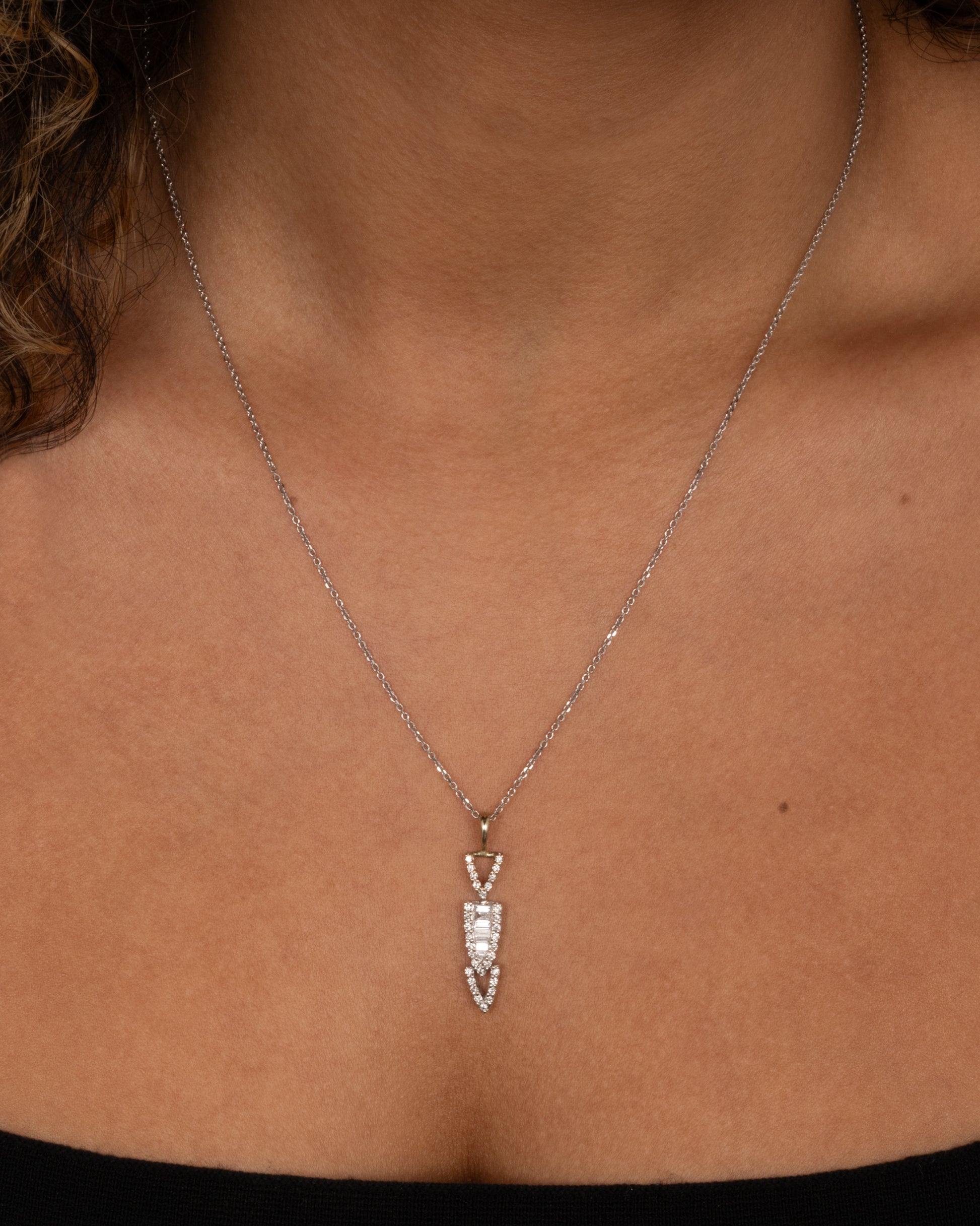 A white gold cable chain necklace with a diamond studded stack of arrows. Shown worn.