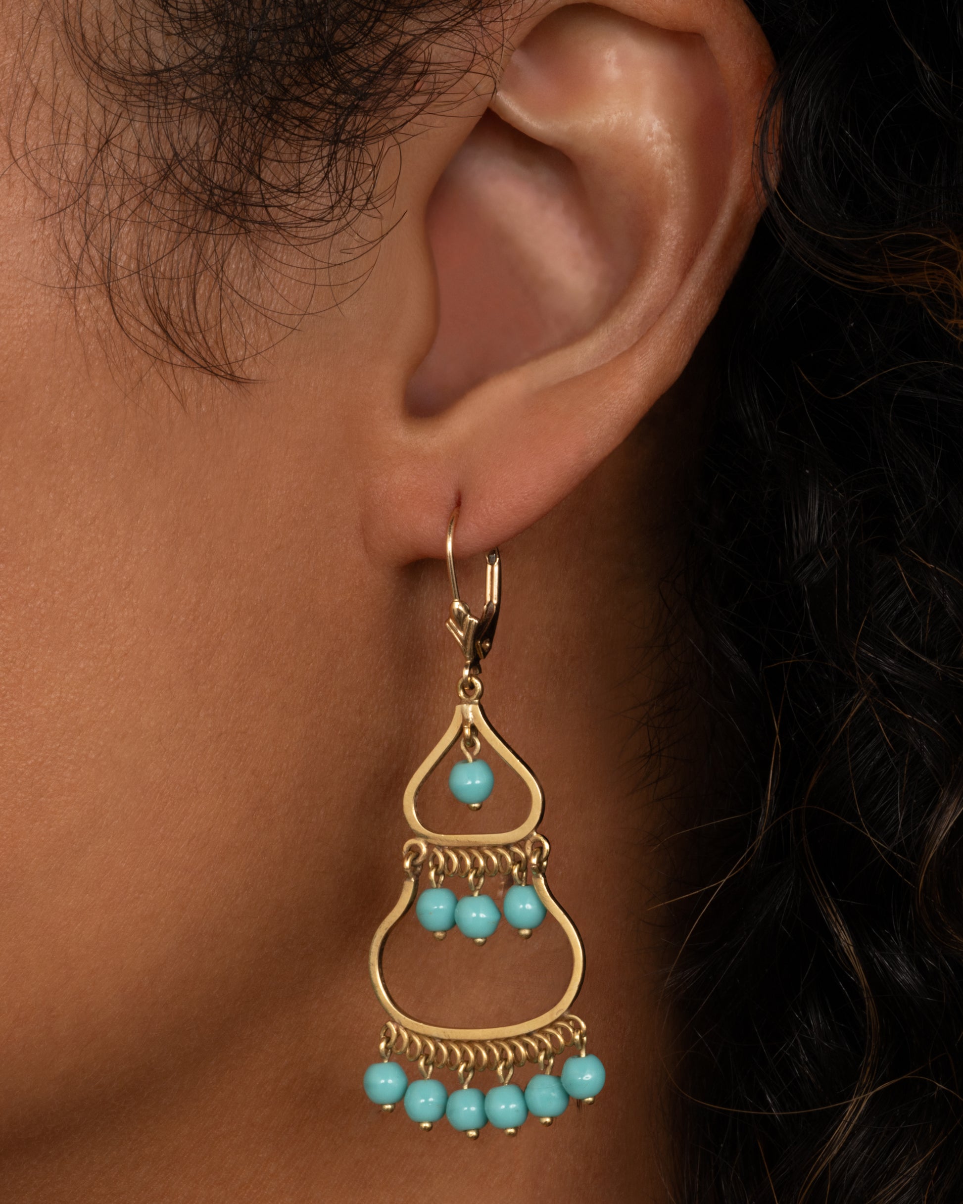 A pair of yellow gold  drop chandelier earrings with turquoise beads, shown worn.