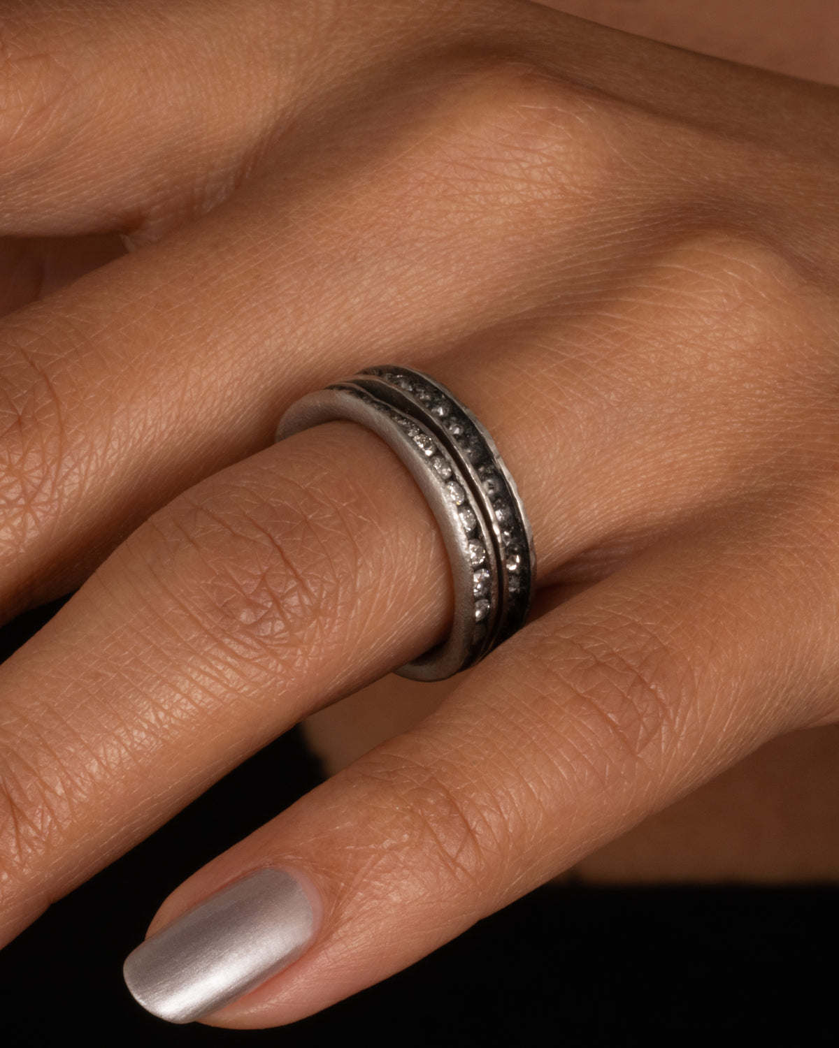 A palladium ring with a queue of diamonds set in a darkened center channel. Shown worn.