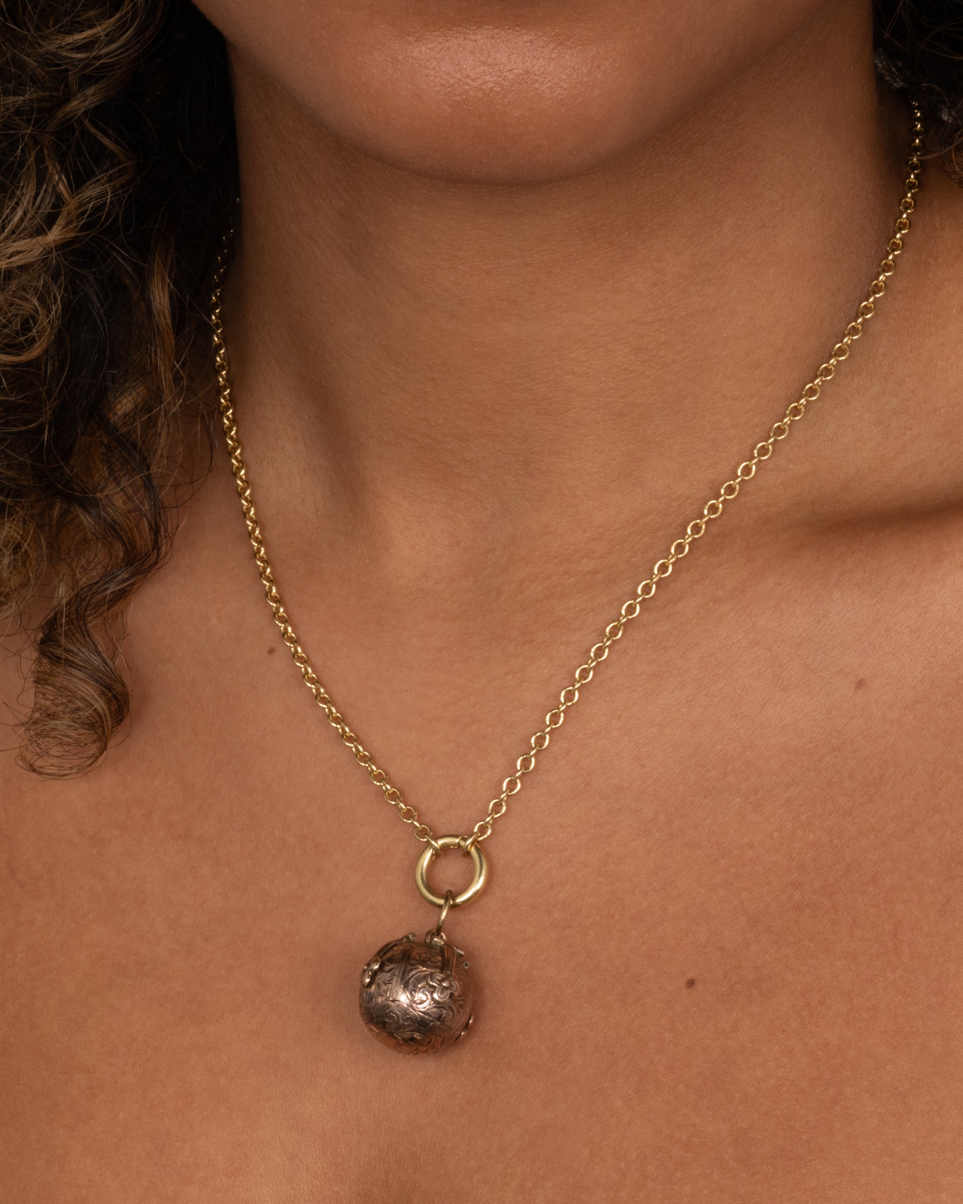 A yellow gold engraved Masonic Orb pendant shown open in a dimensional cross shape. 