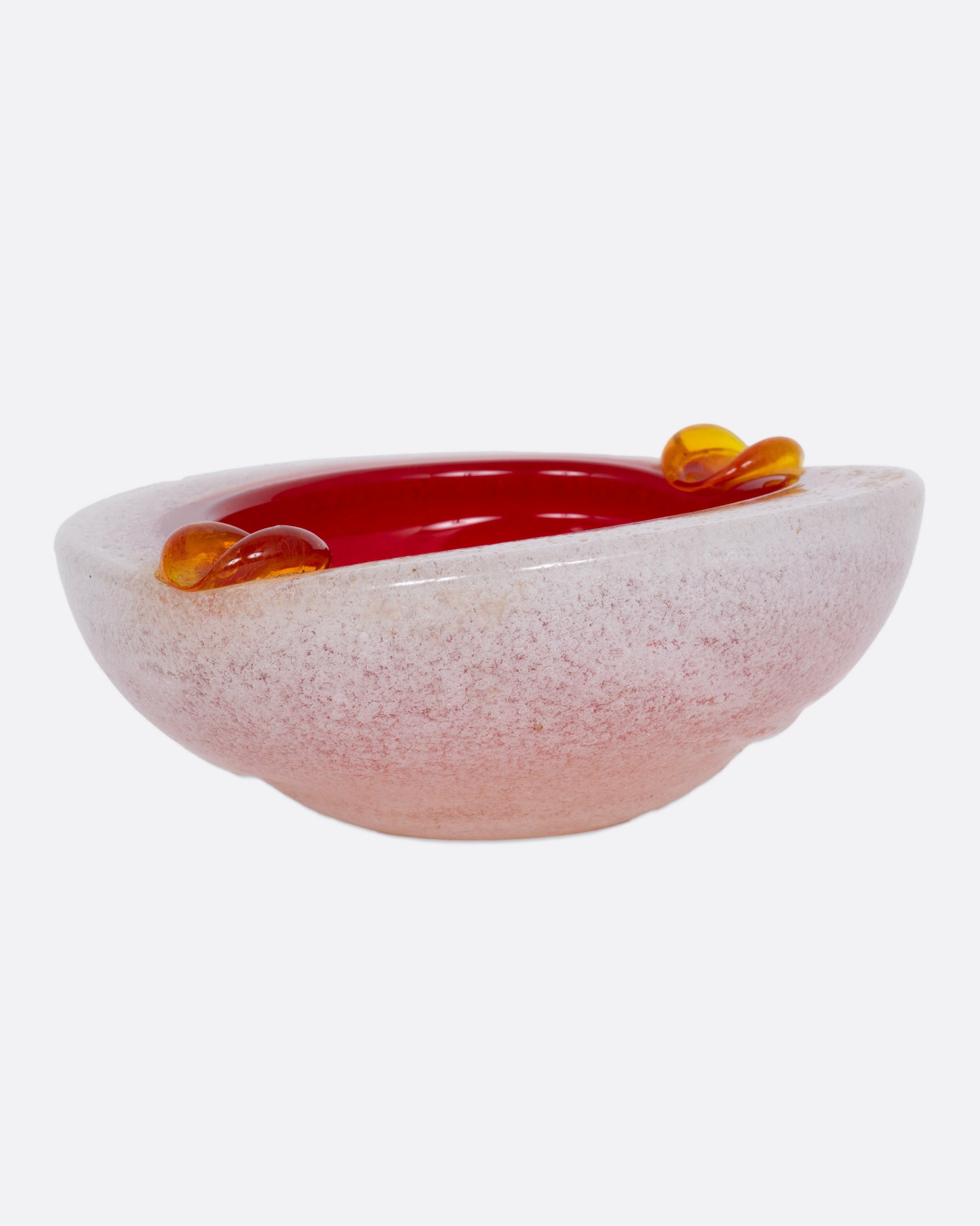 An orange and white blown glass ashtray, shown from the side.