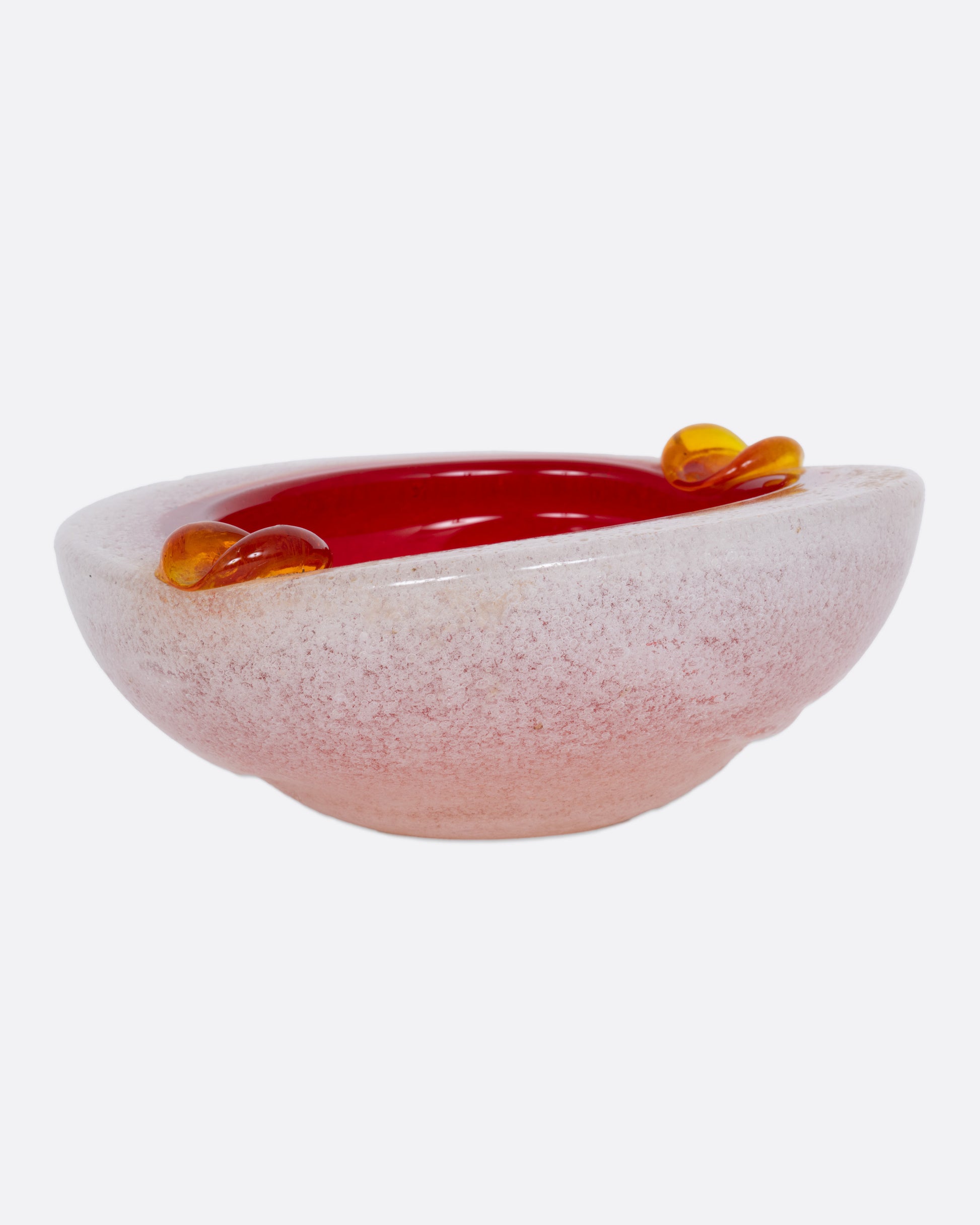 An orange and white blown glass ashtray, shown from the side.