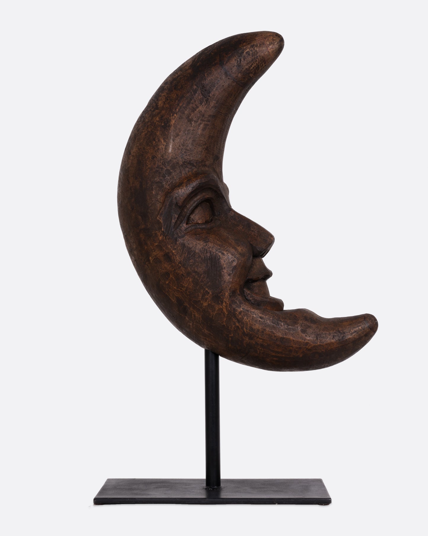 A wooden crescent moon takaan sculpture with a face on a black stand shown from the side.