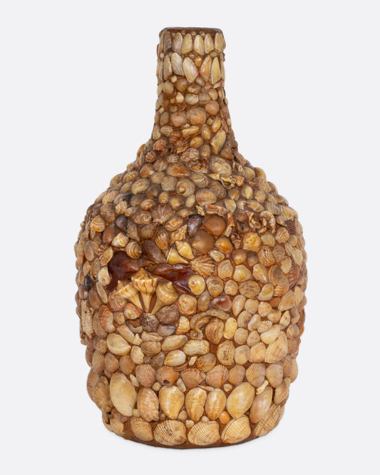 A bottle covered in shells to create a mosaic, shown from the front.