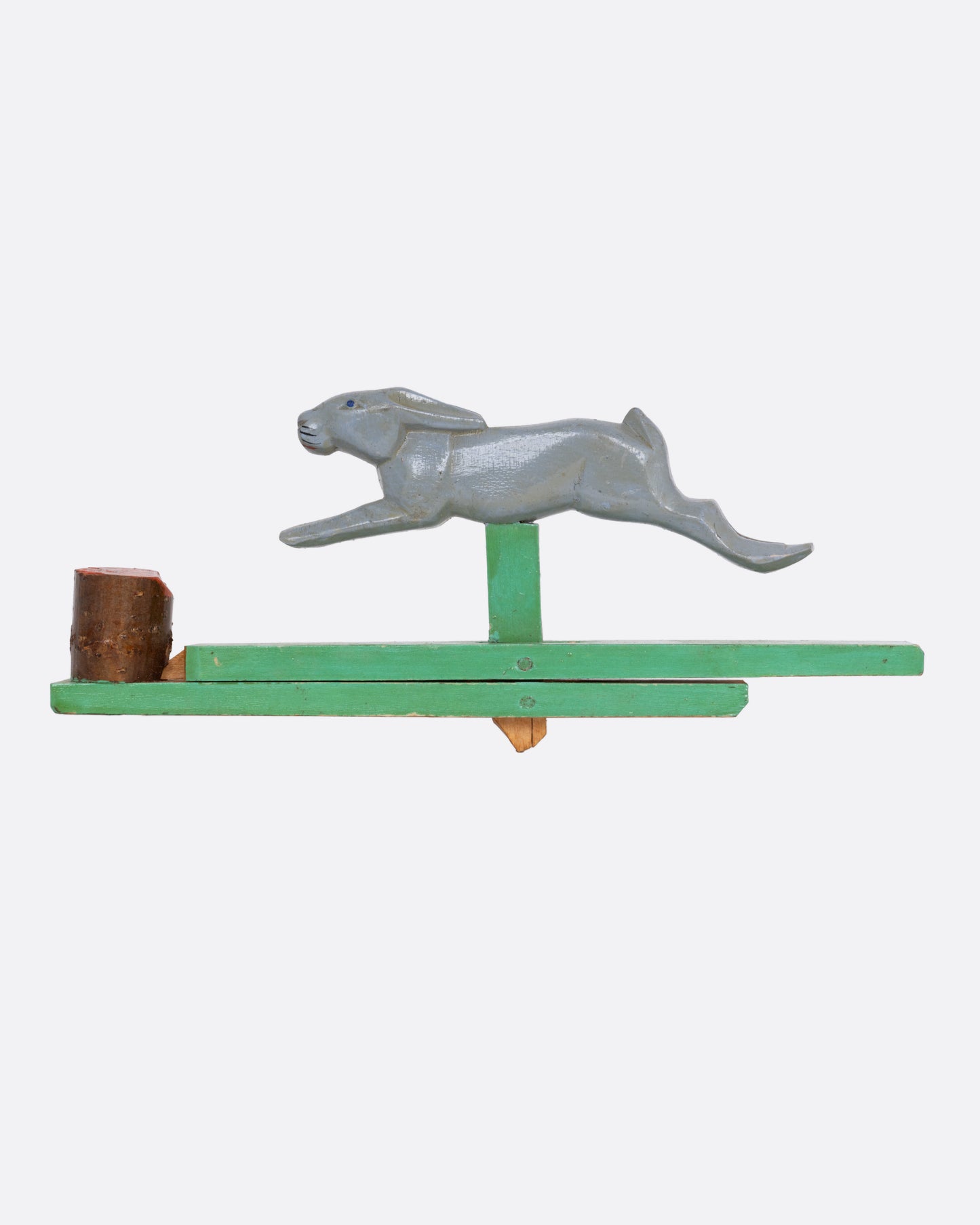 A wooden toy rabbit on a green wooden base, shown from the side.