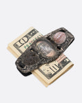 A textural silver money clip with a  pebble, quartz, and seashell set in the front, shown from the front with a folded ten dollar bill in it.
