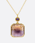 A yellow gold pendant necklace with an ametrine sunset carving with a gold sun face on its reverse. A round amethyst hovers just above this double sided pendant. Shown from the front.