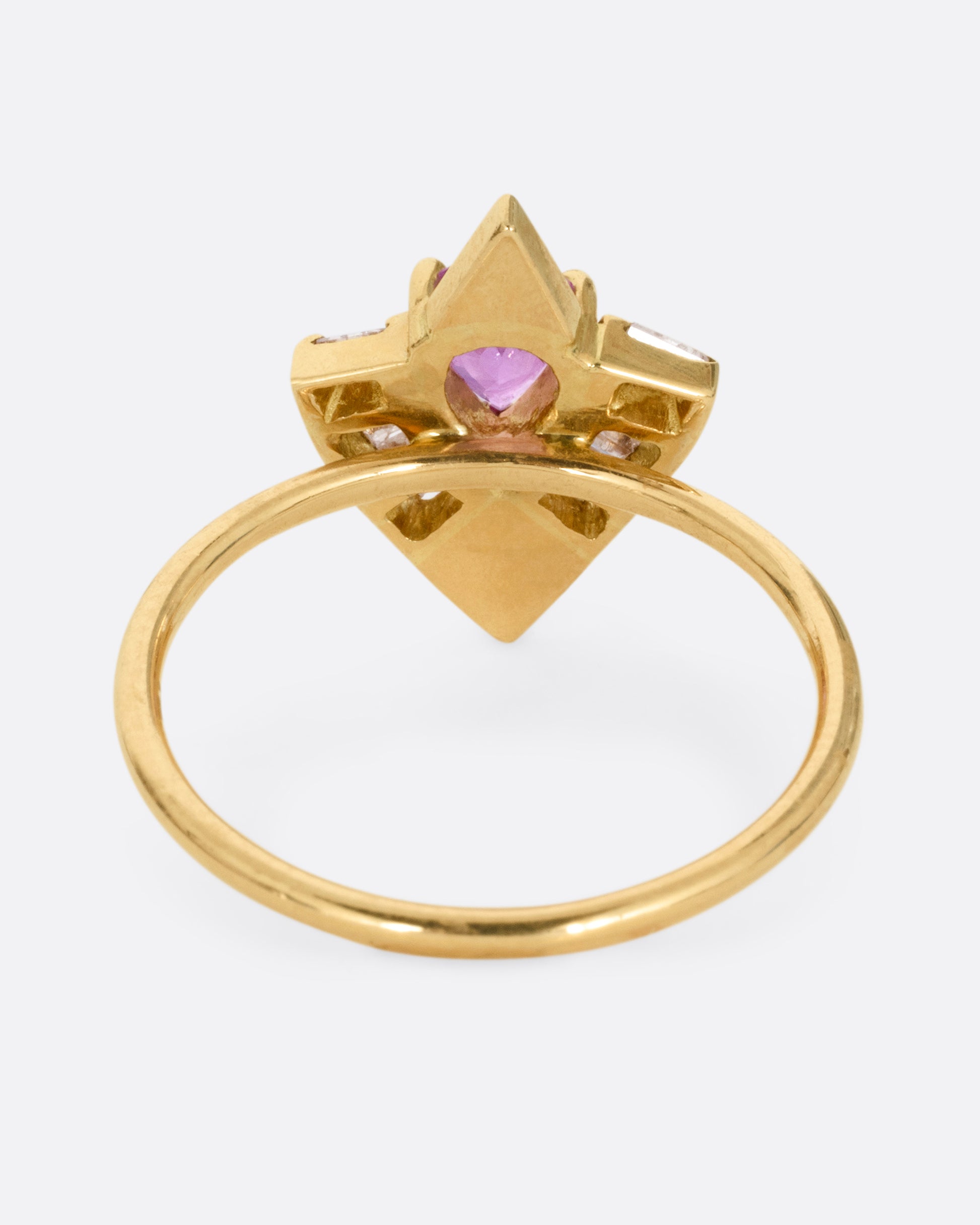 A yellow gold ring with a pink sapphire and baguette diamonds, shown from the back.