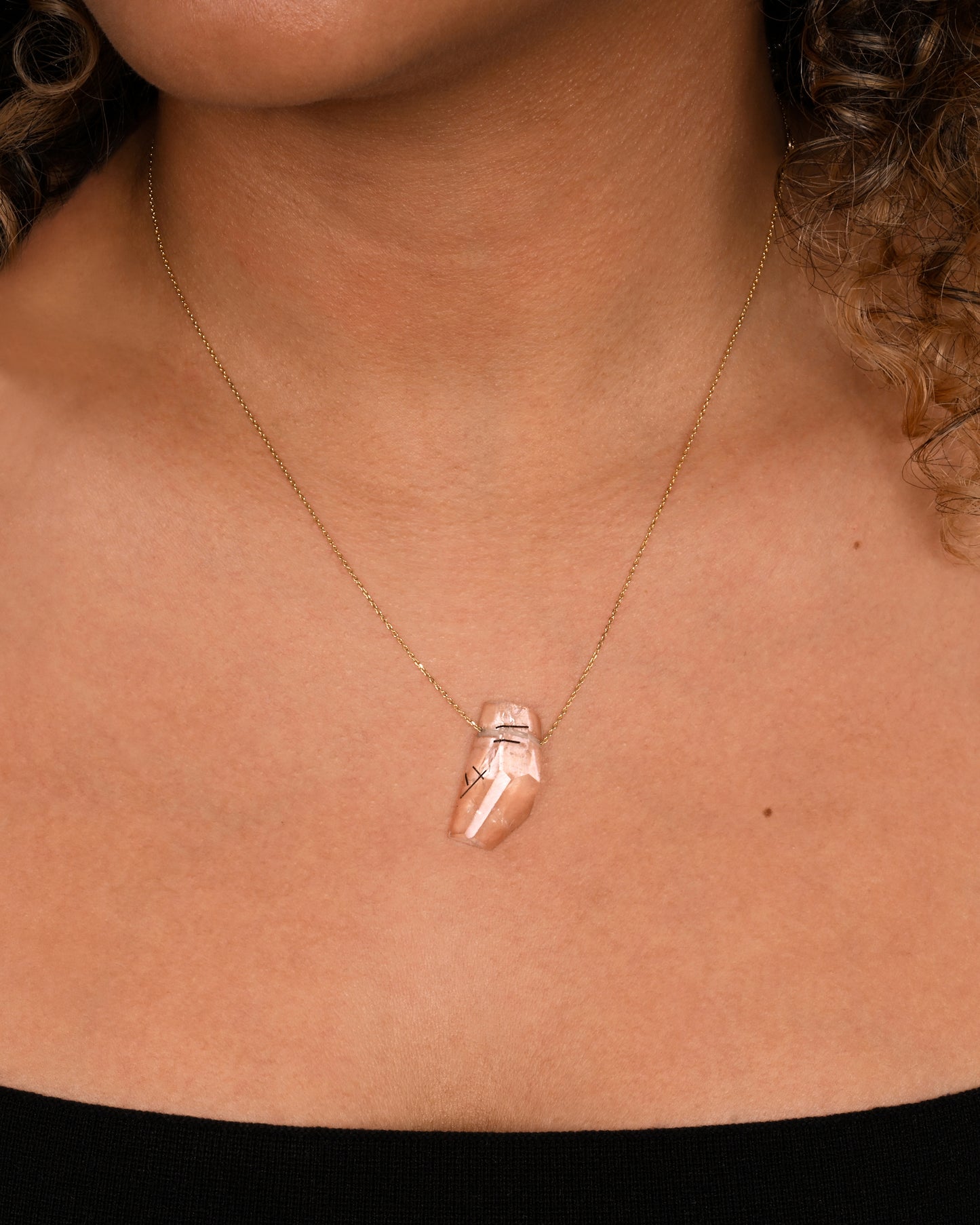 A drilled tourmalinated quartz on a fine yellow gold chain. Shown worn around the neck.