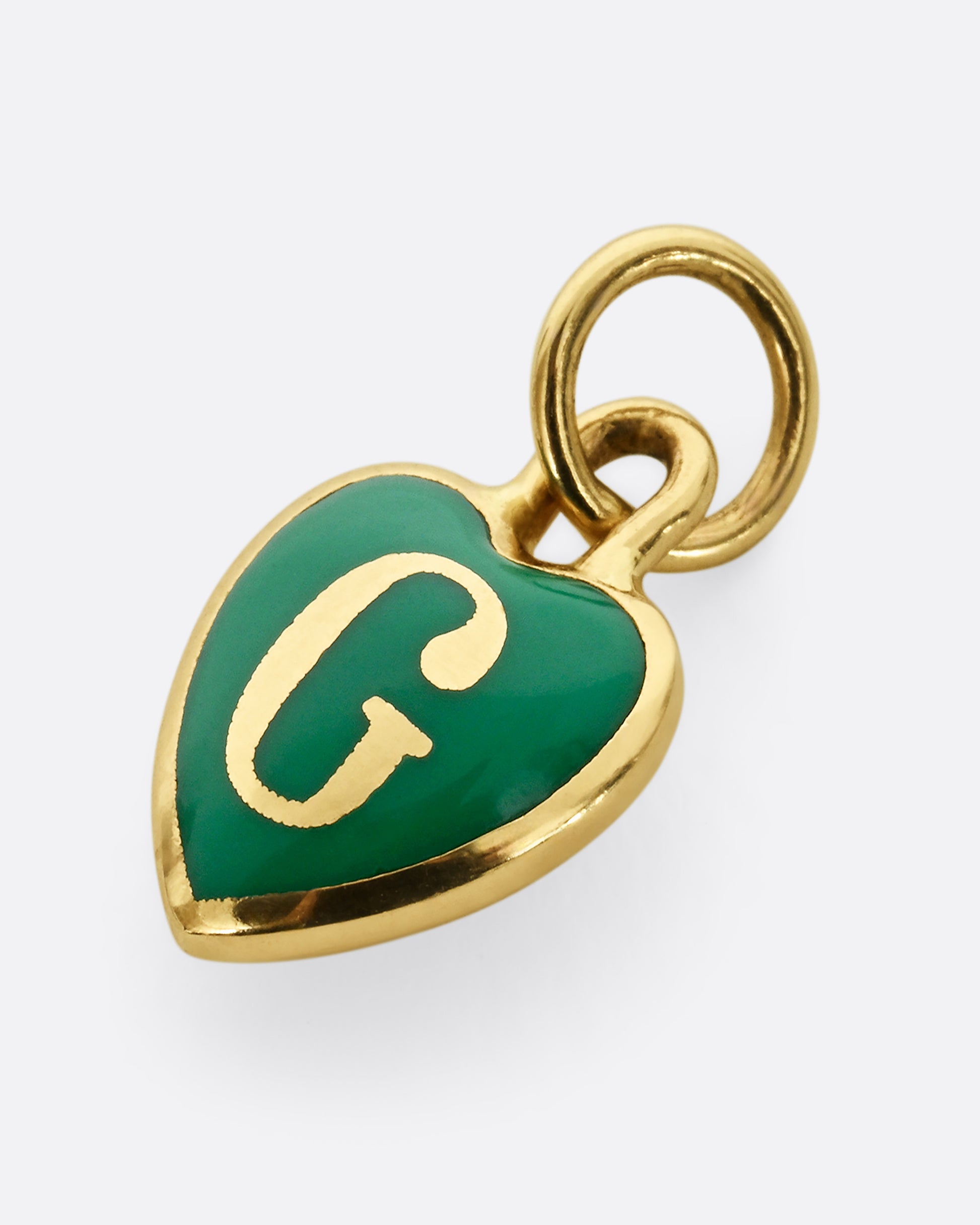 A yellow gold heart shaped pendant with green enamel and a letter G, shown from the front.