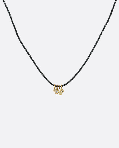 An oxidized silver beaded necklace with four different diamond charms. Shown from the front.