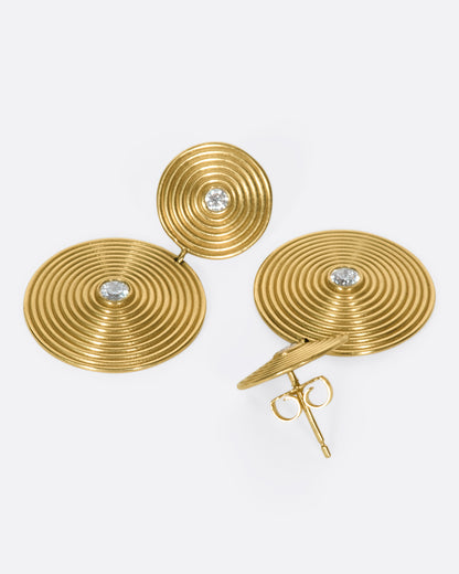 Yellow gold diamond disc drop earrings, the pair laid flat, one showing the post and back