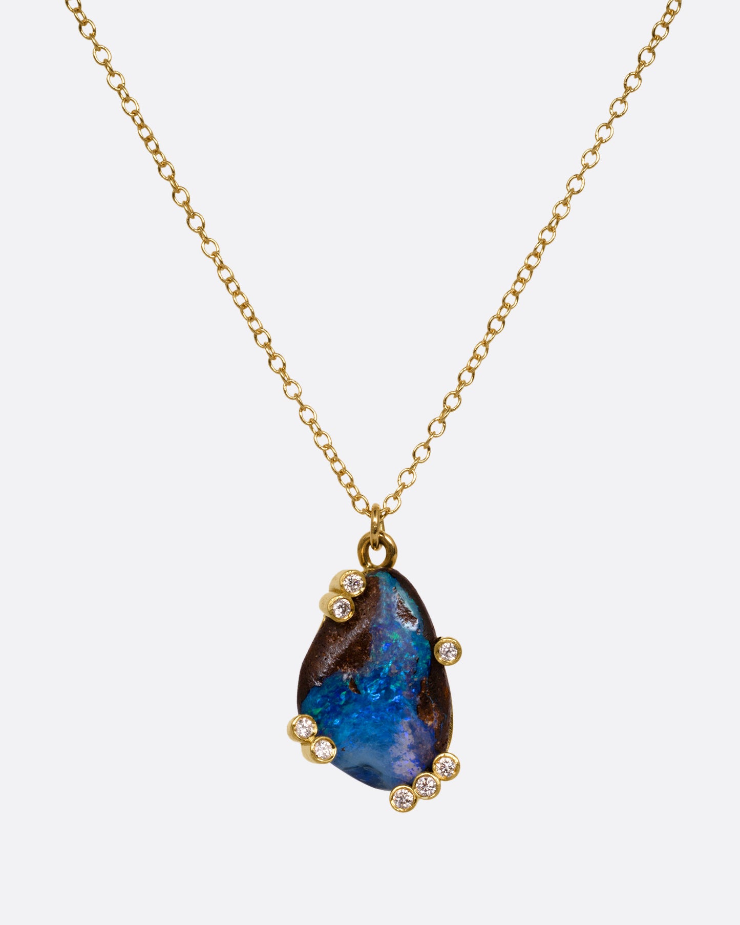 A yellow gold cable chain necklace with diamond studded gold anemones around a free-form boulder opal pendant, shown from the front.