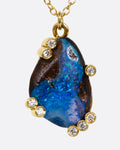 A yellow gold cable chain necklace with diamond studded gold anemones around a free-form boulder opal pendant, shown from the front.
