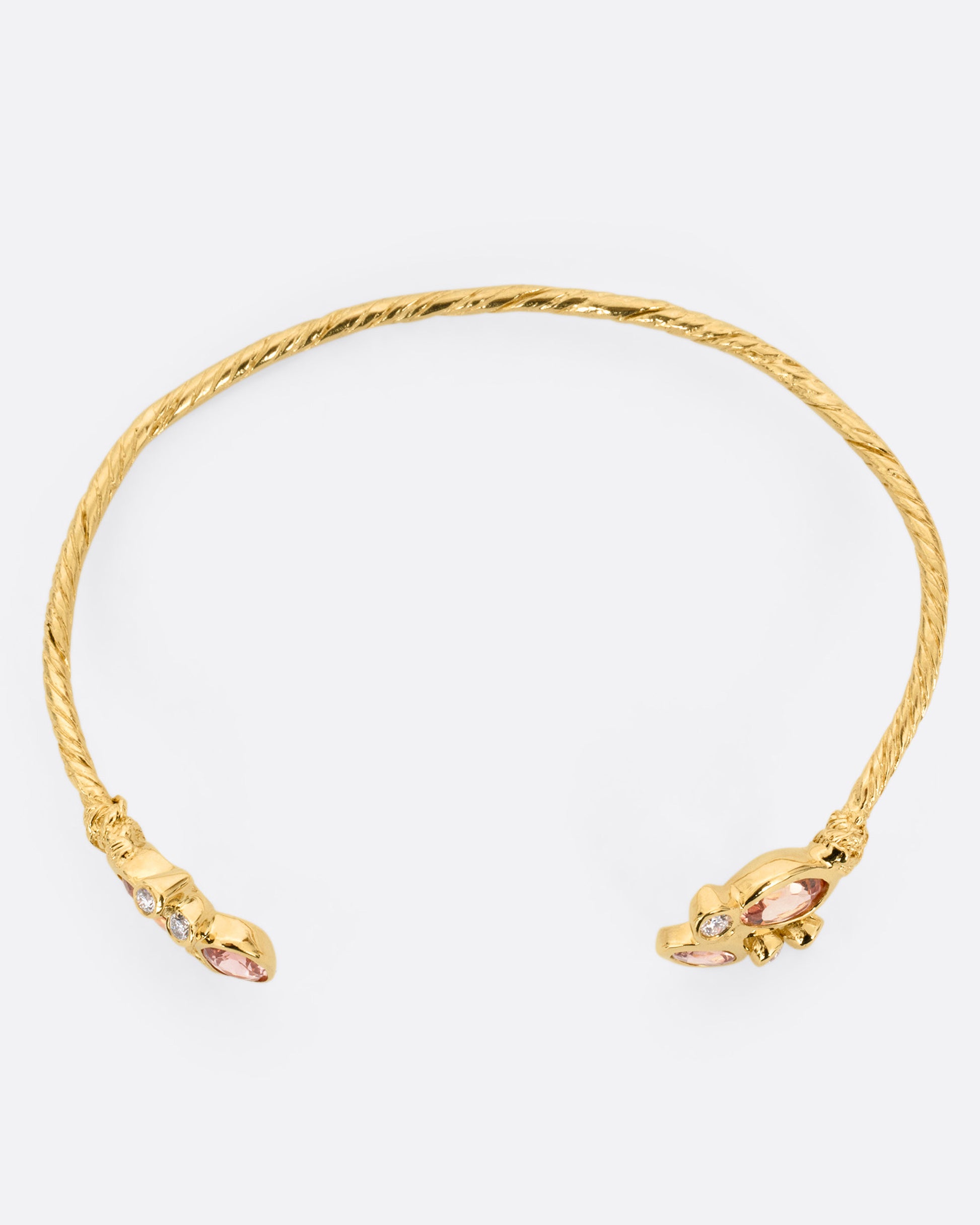 A yellow gold hand carved cuff bracelet with clusters of tourmalines and diamonds on either side of its open front, shown from the top.