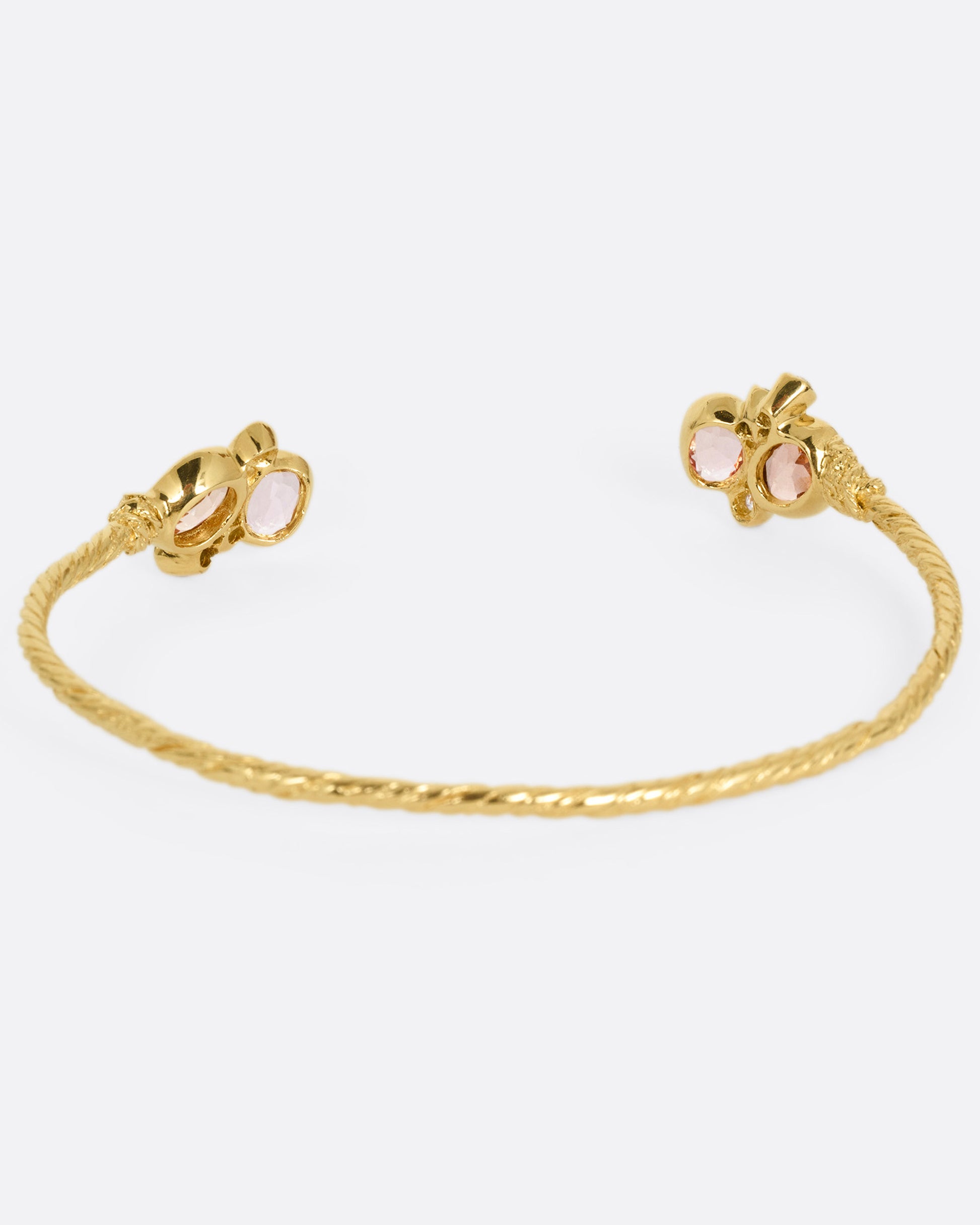 A yellow gold hand carved cuff bracelet with clusters of tourmalines and diamonds on either side of its open front, shown from the back.