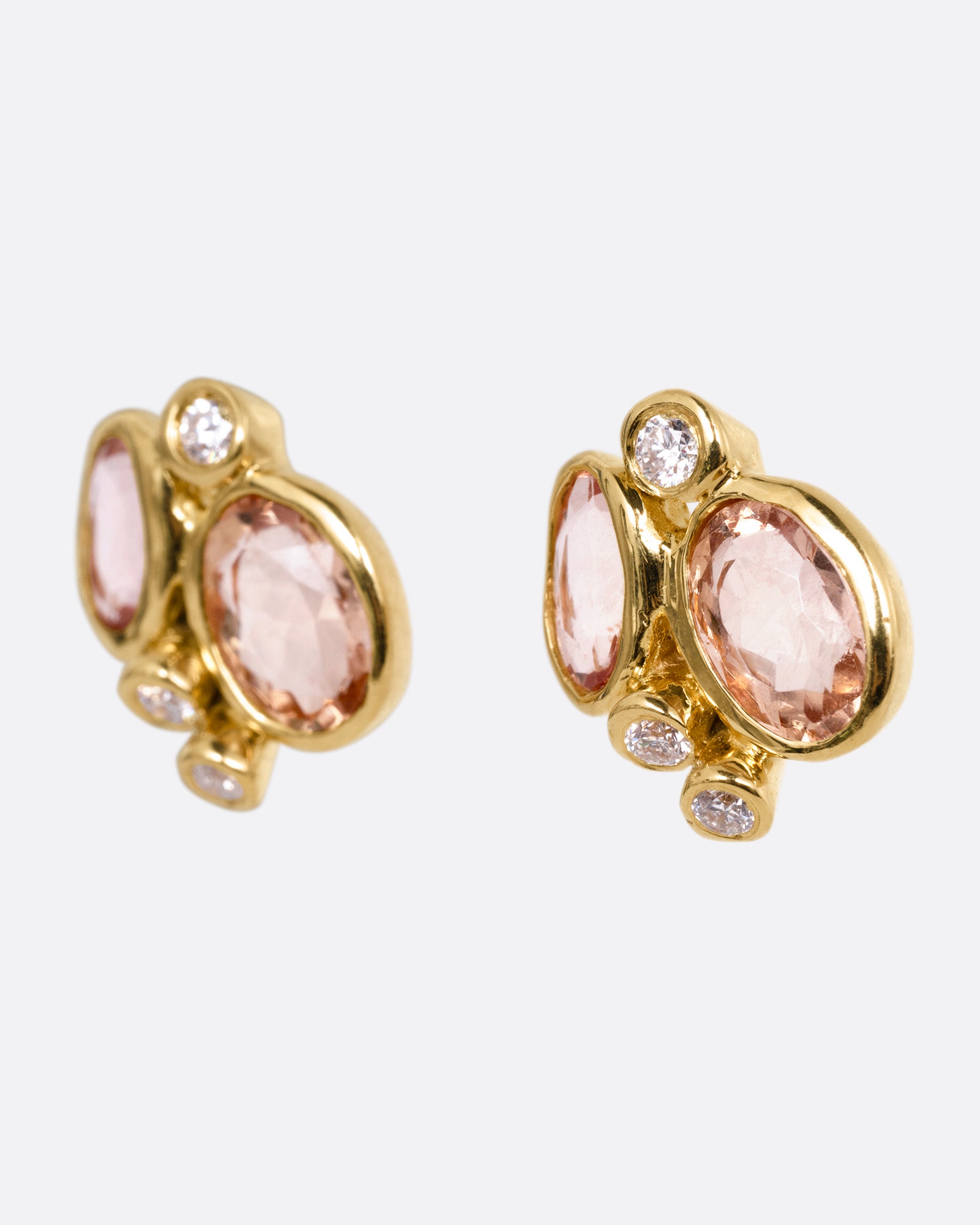 A pair of yellow gold stud earrings with clusters of pink tourmalines and white diamonds, shown from the side.