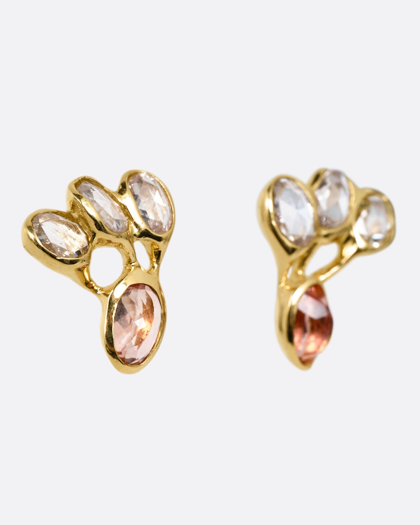 A pair of yellow gold stud earrings with freeform rose cut diamonds and pink tourmalines, shown from the side.