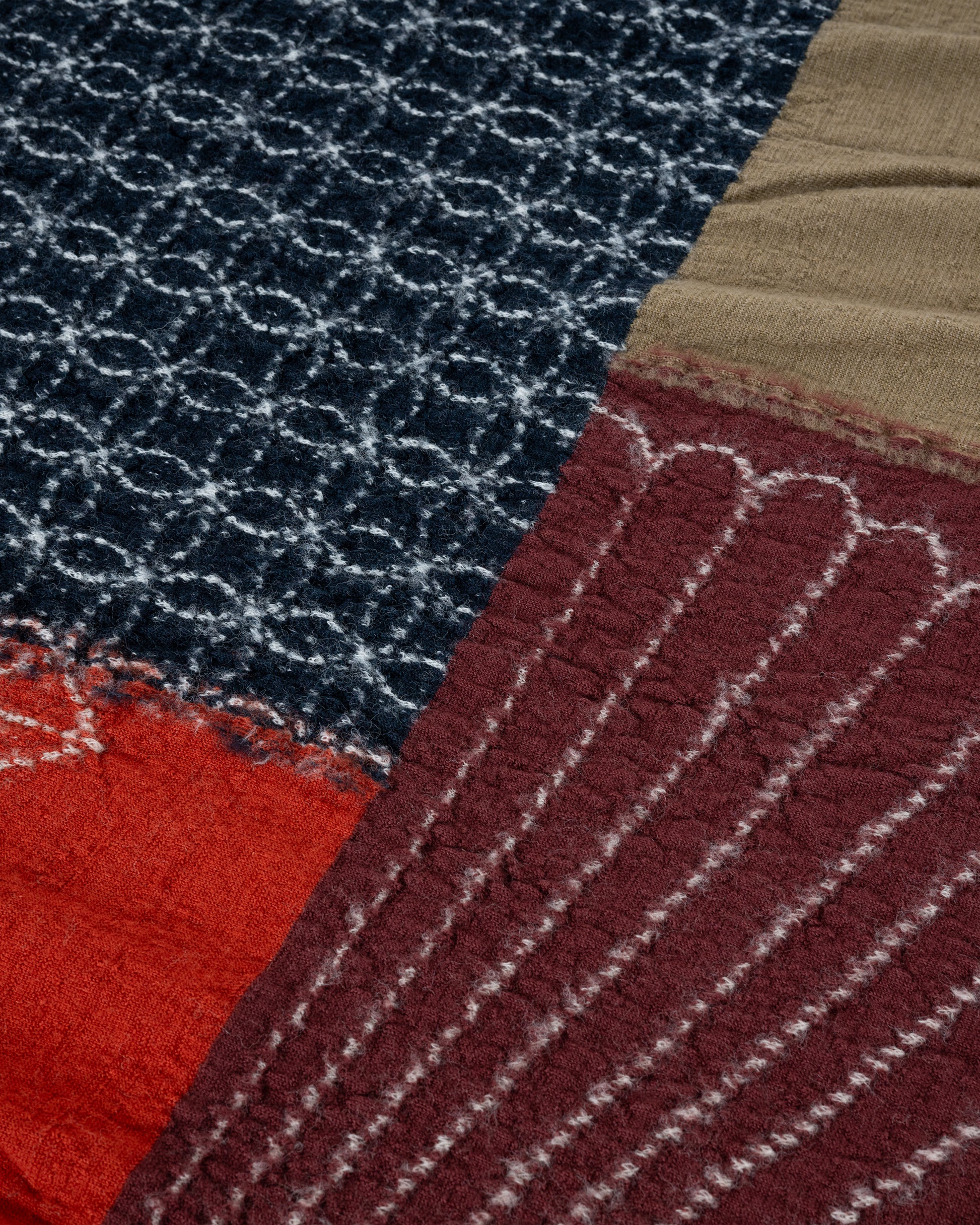 A red patchwork wool scarf. Close up of pattern.