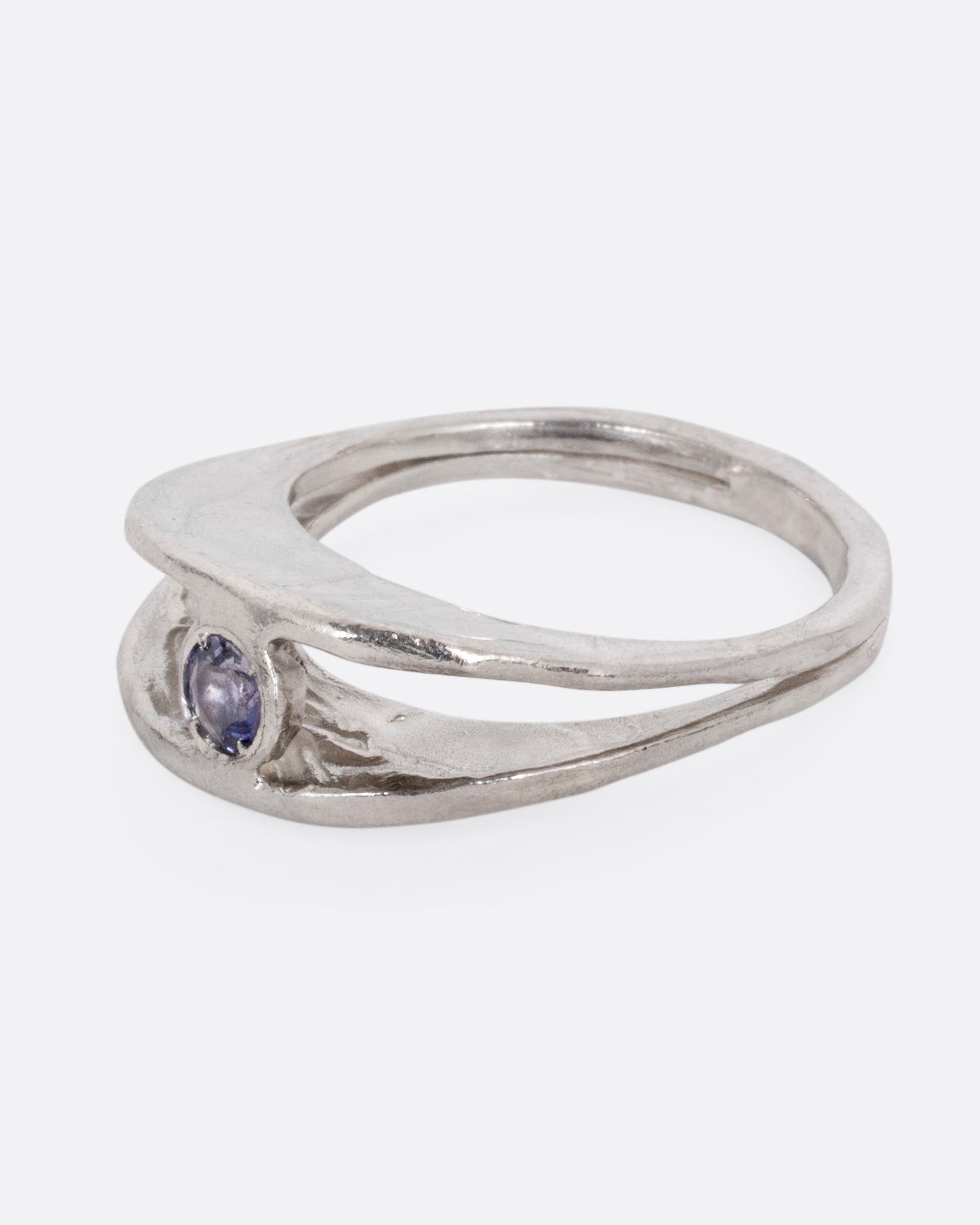 A silver ring with a split shank and a center iolite, shown from the side.
