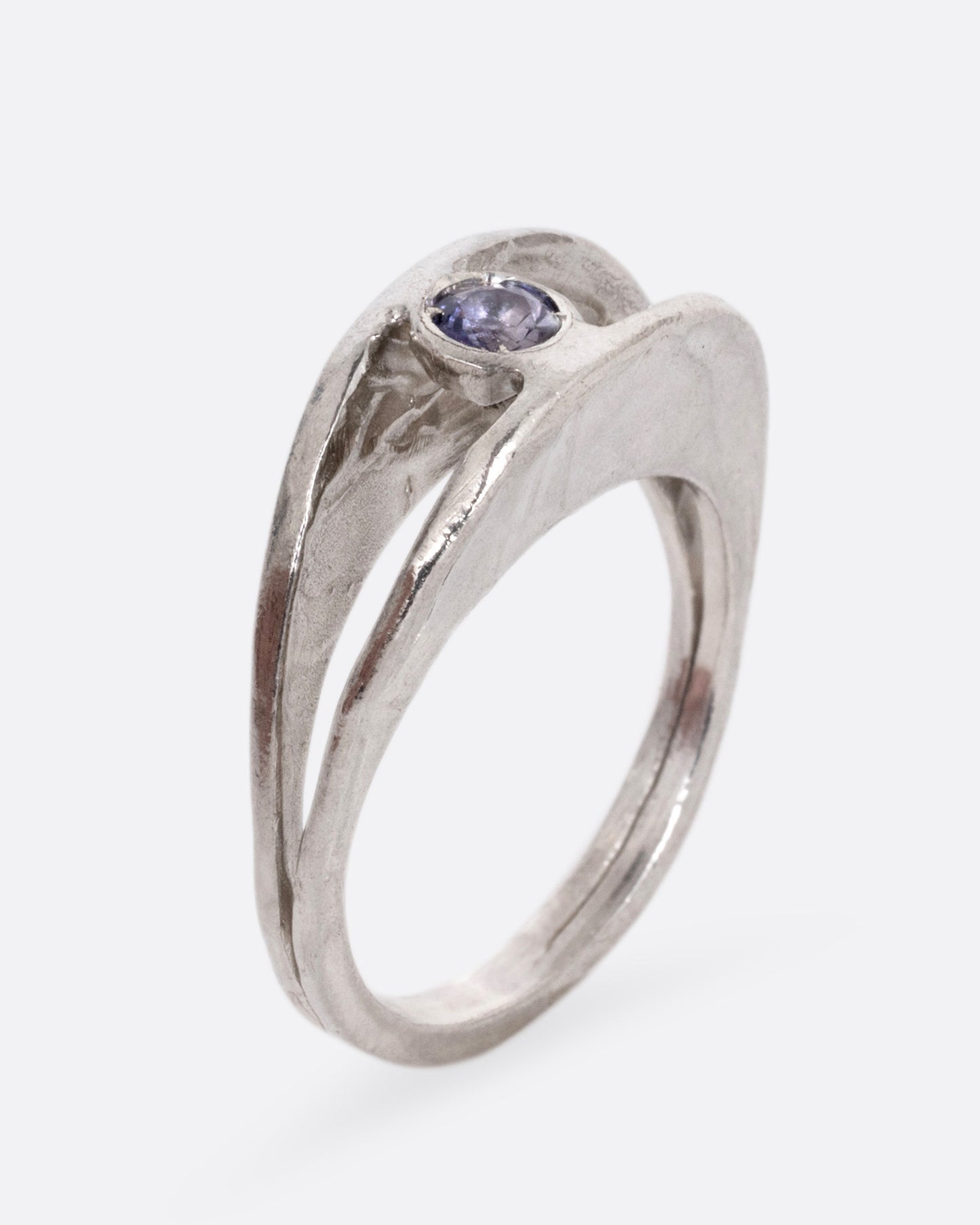 A silver ring with a split shank and a center iolite, shown from the side standing up.