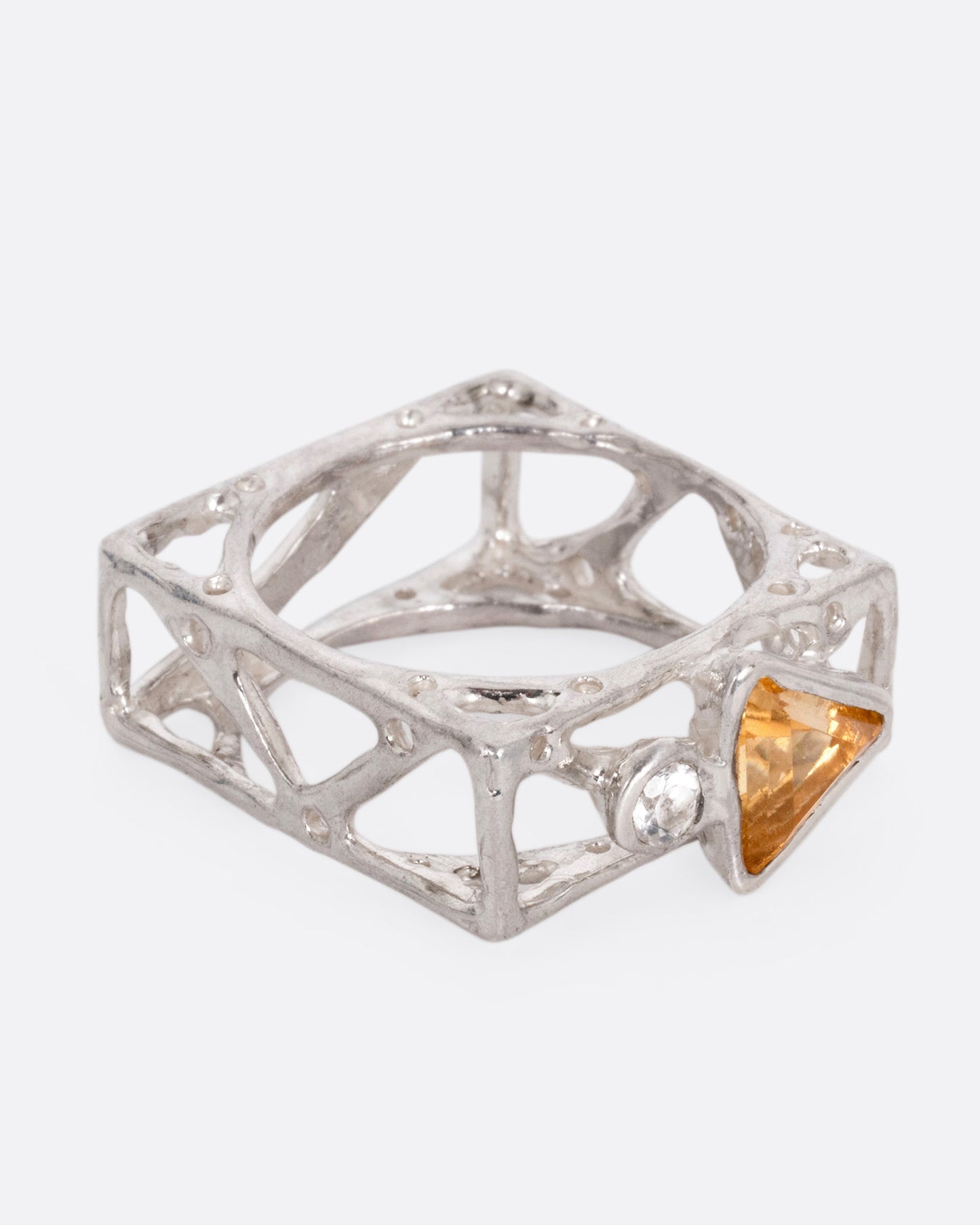 A silver stacked square ring with cutouts and a triangular citrine and a round topaz, shown from the side.