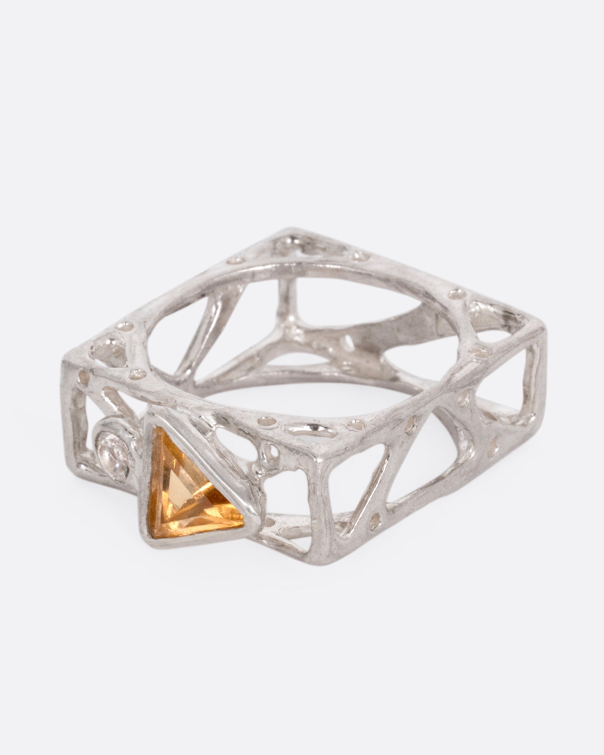 A silver stacked square ring with cutouts and a triangular citrine and a round topaz, shown from the side.