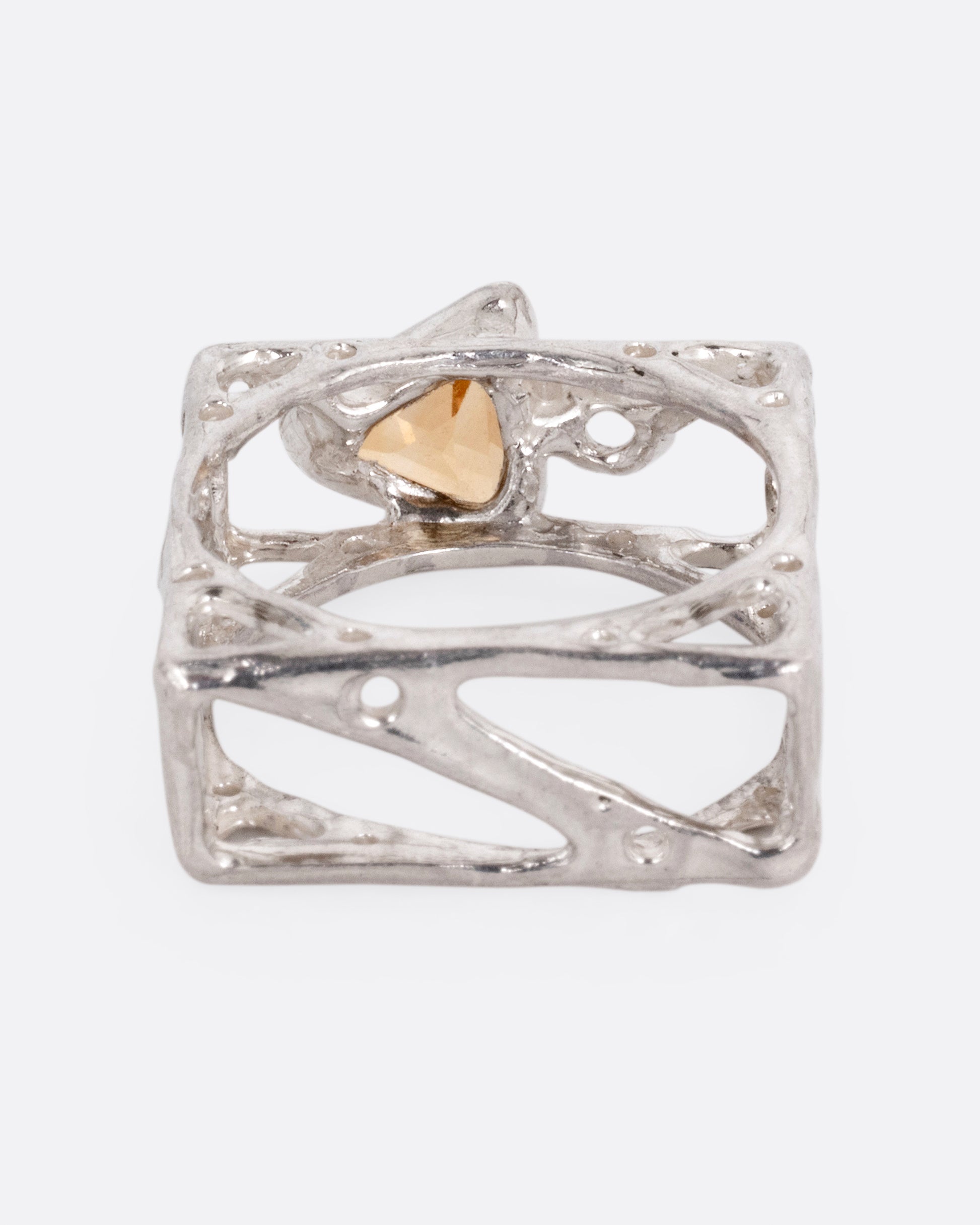 A silver stacked square ring with cutouts and a triangular citrine and a round topaz, shown from the back.