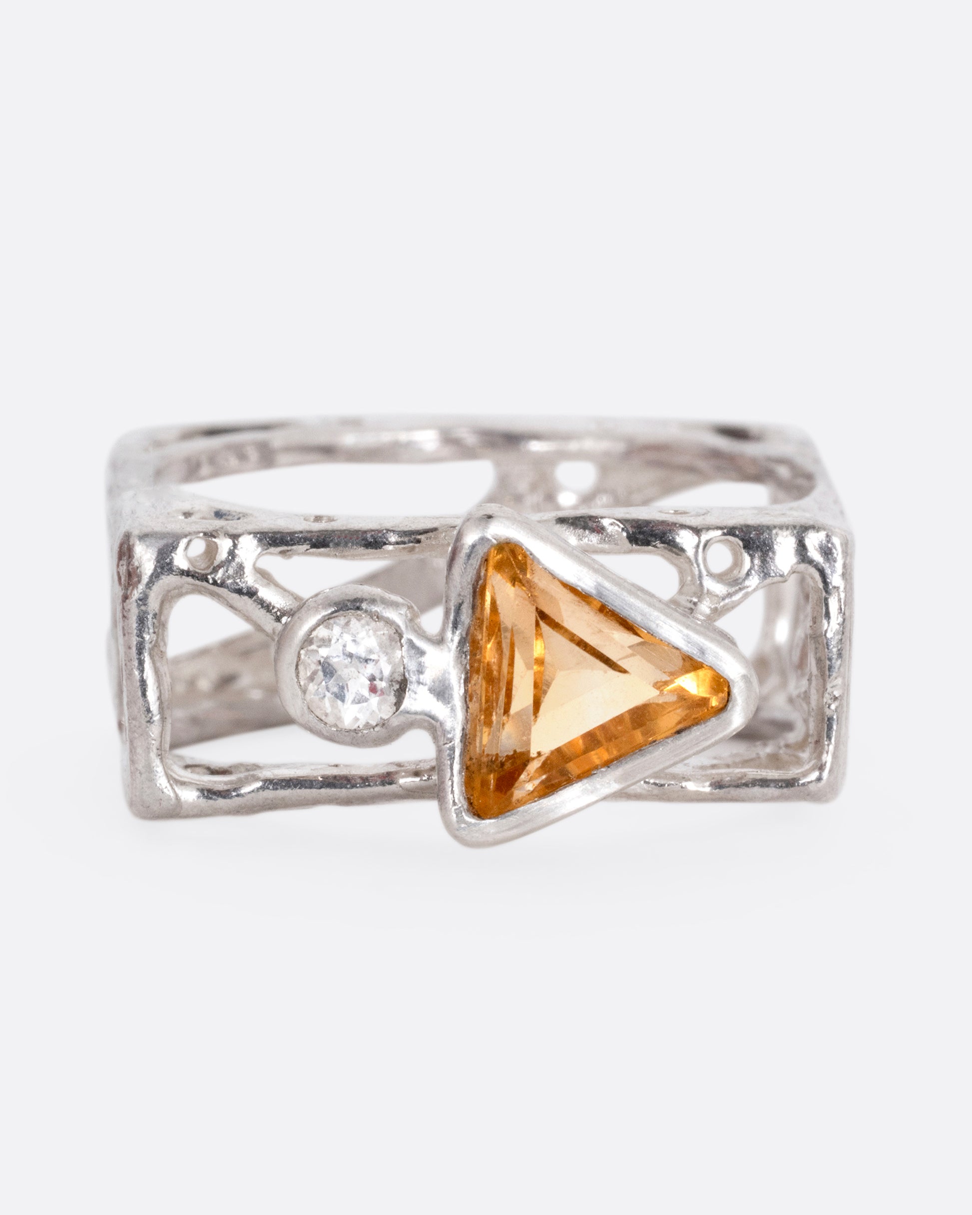 A silver stacked square ring with cutouts and a triangular citrine and a round topaz, shown from the front.