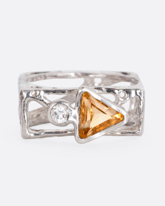 A silver stacked square ring with cutouts and a triangular citrine and a round topaz, shown from the front.
