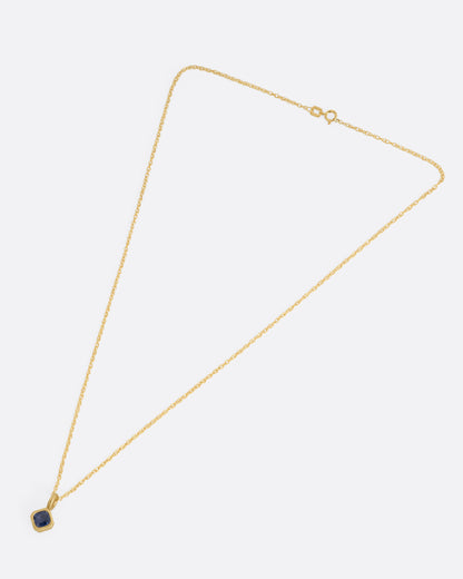 Yellow gold blue sapphire pendant necklace laid flat, showing the chain length and clasp