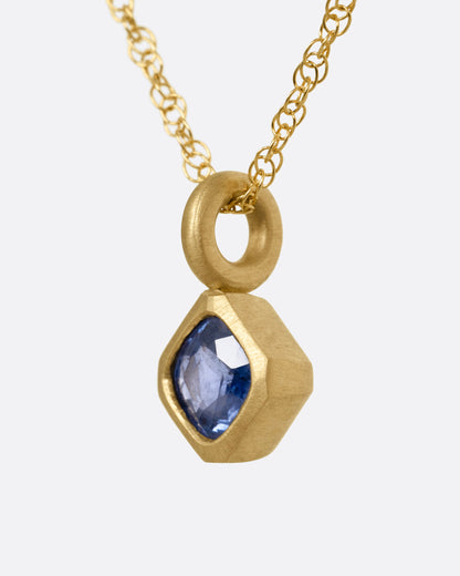 Yellow gold blue sapphire pendant necklace, side view showing the bail and bezel
