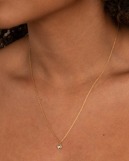 A yellow gold cable chain necklace with a dimensional diamond heart pendant, shown from the front on a person.